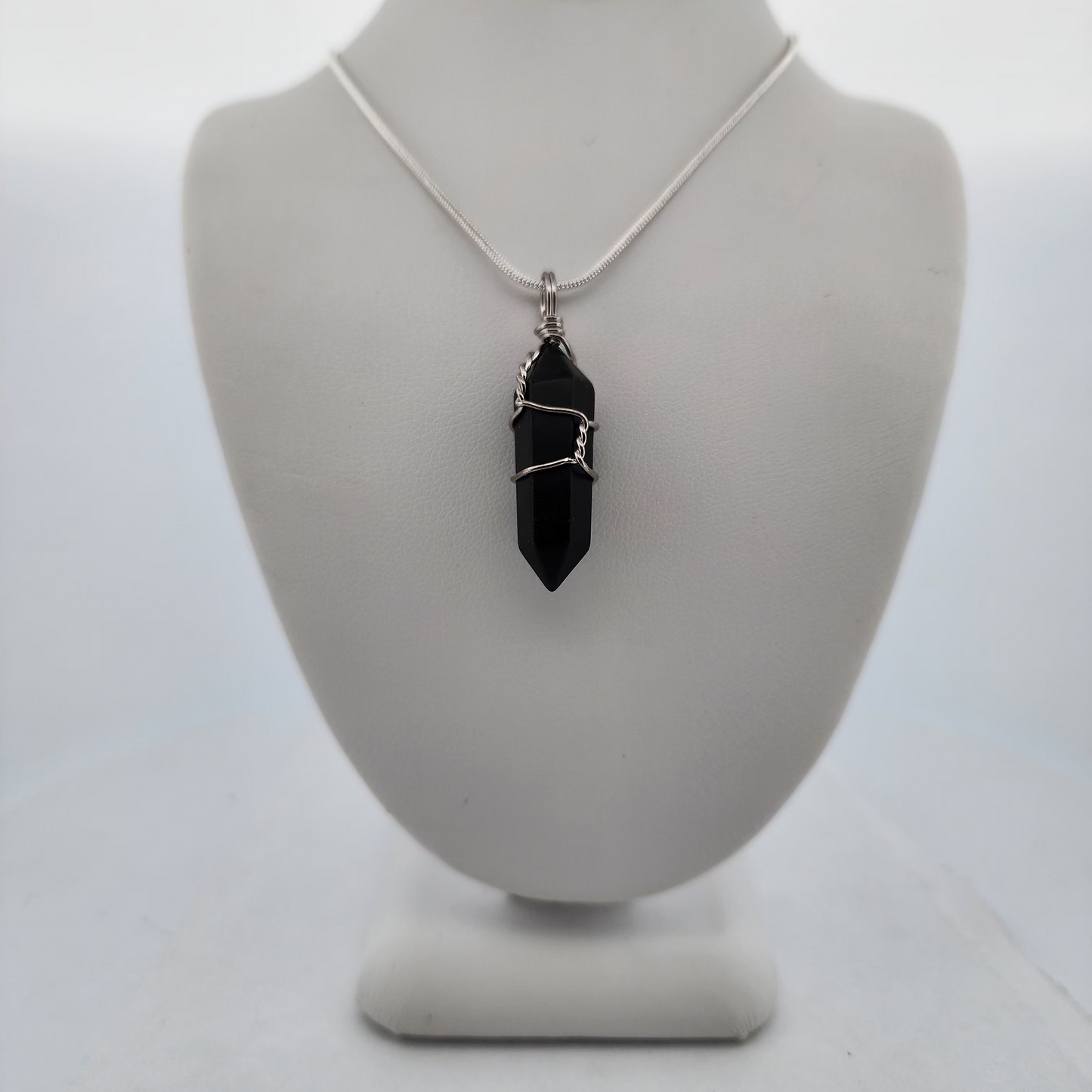 Necklace with a black pendant on a white mannequin bust against a white background