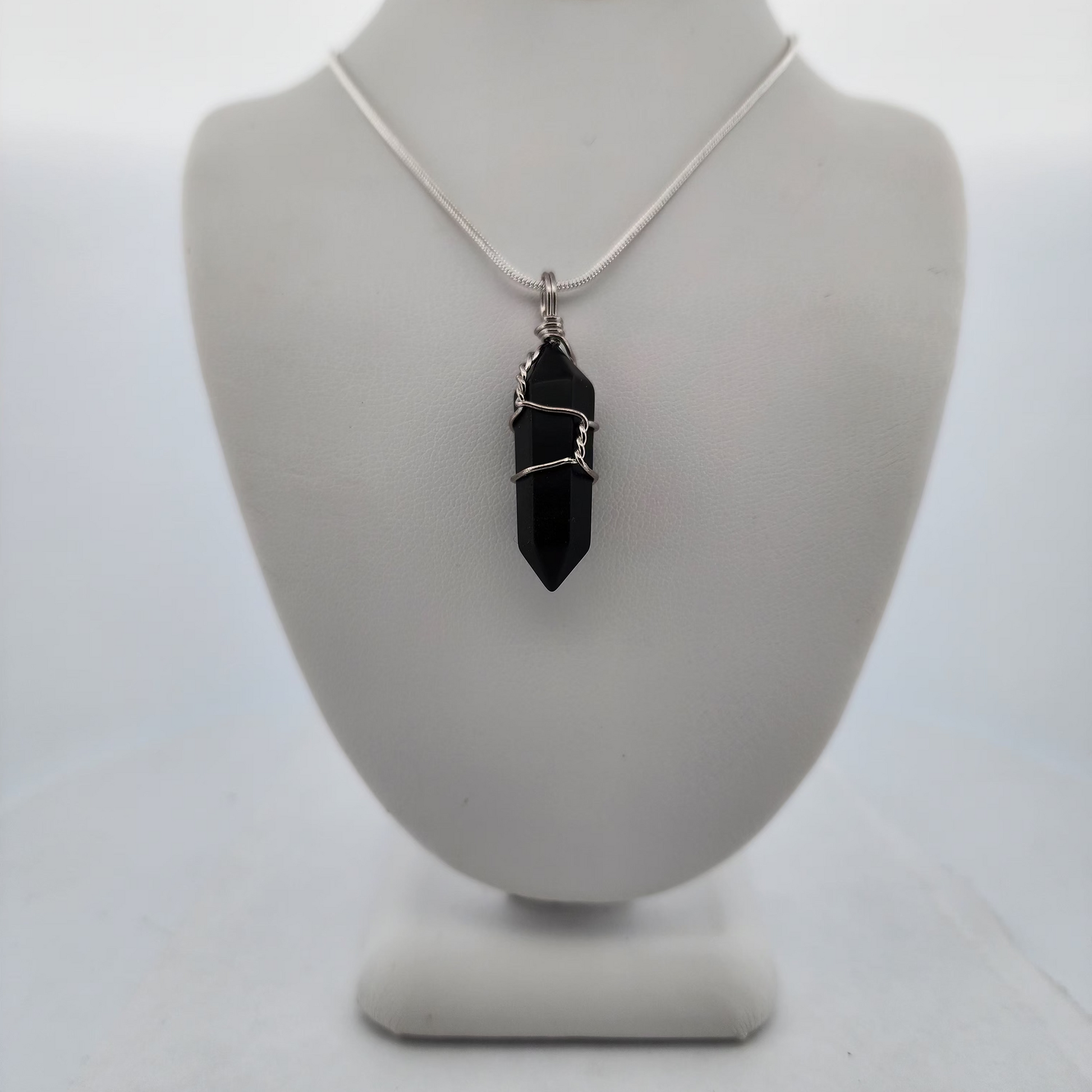 Necklace with a black pendant on a white mannequin bust against a white background
