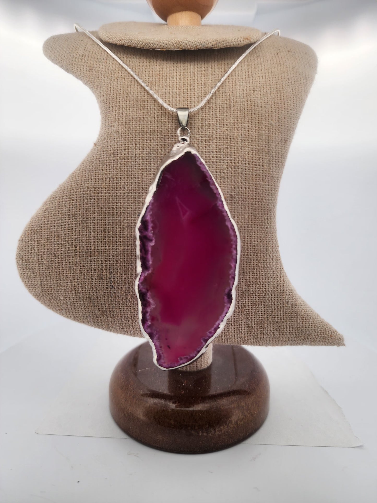 Necklace with a pink agate pendant on a mannequin bust.