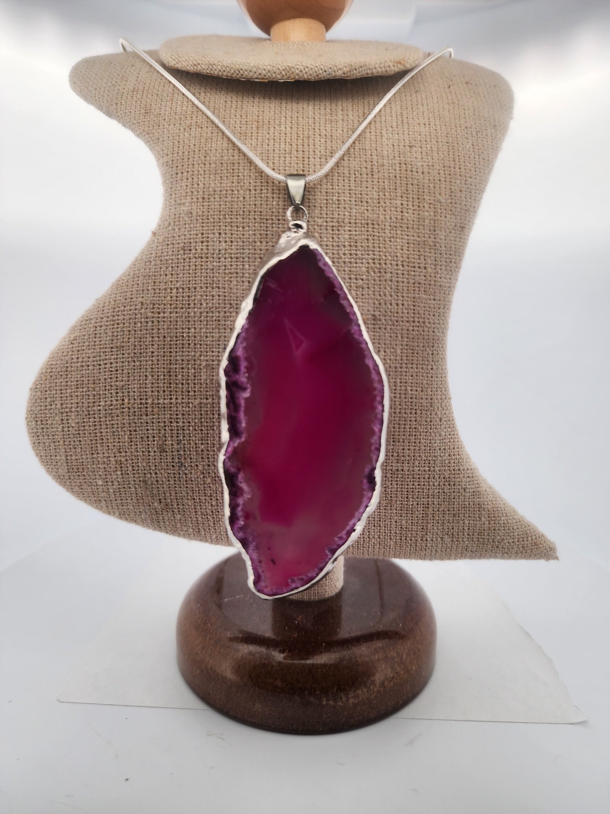 Necklace with a pink agate pendant on a mannequin bust.