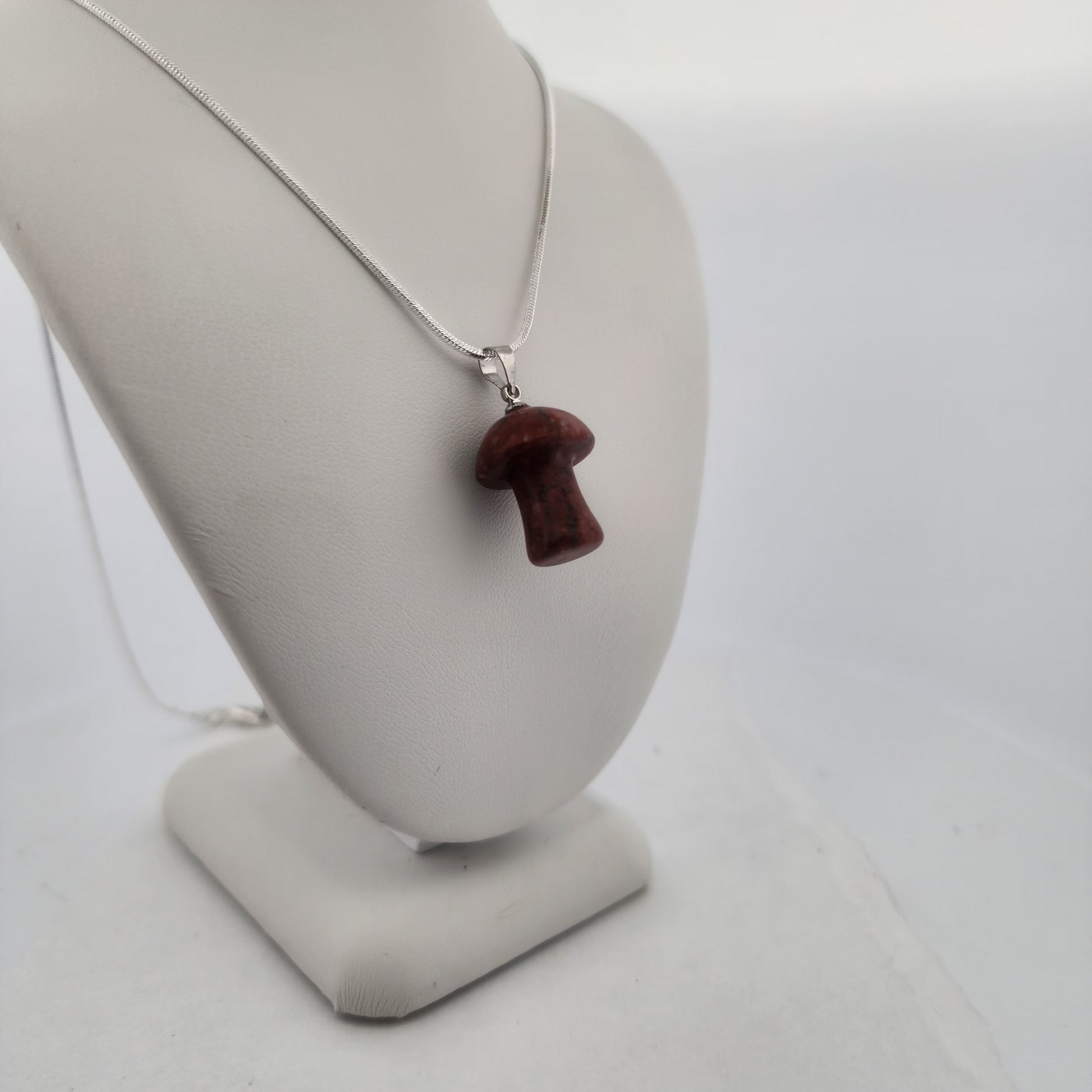 Necklace with a red mushroom pendant on a mannequin bust against a white background
