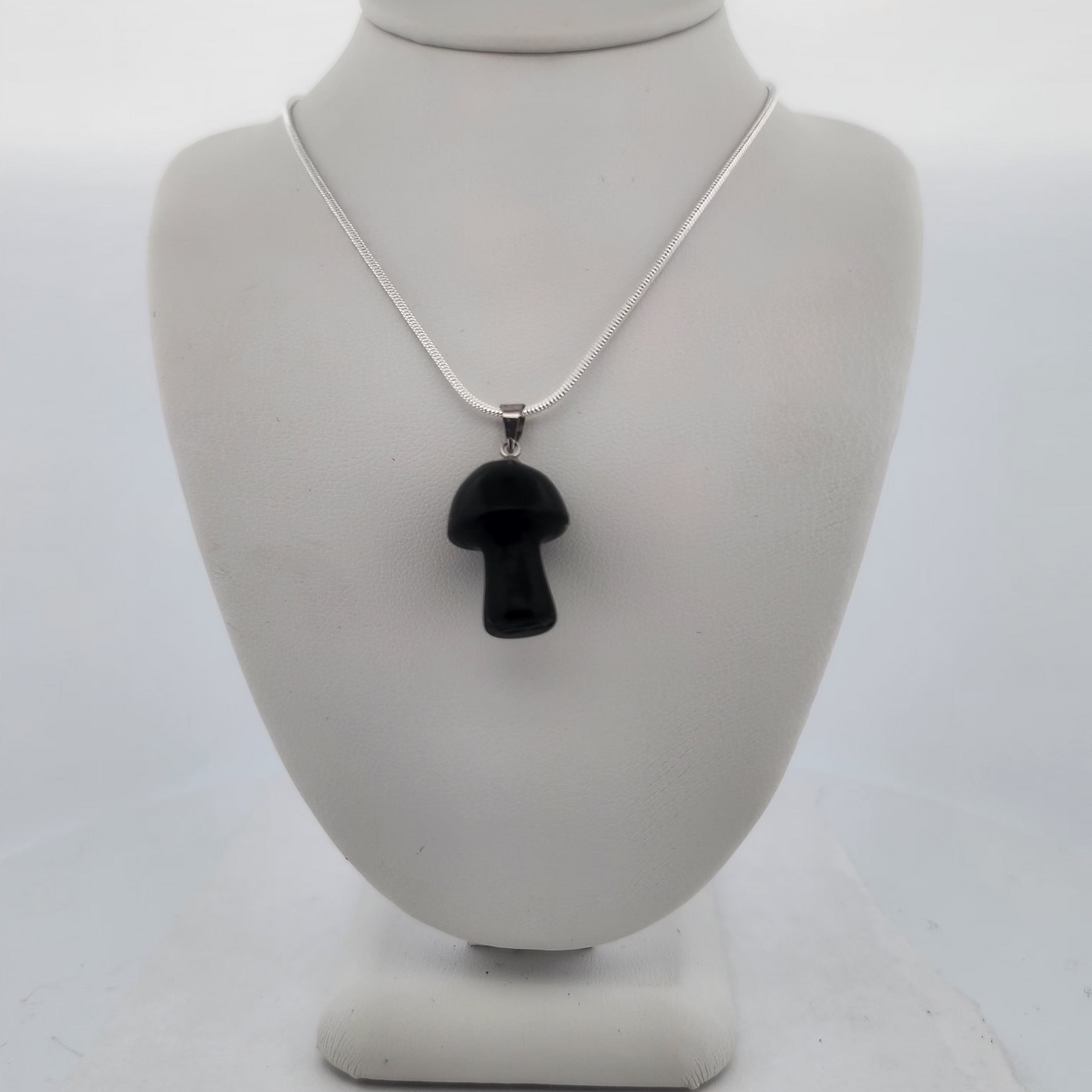 Black pendant on a silver chain displayed on a white bust