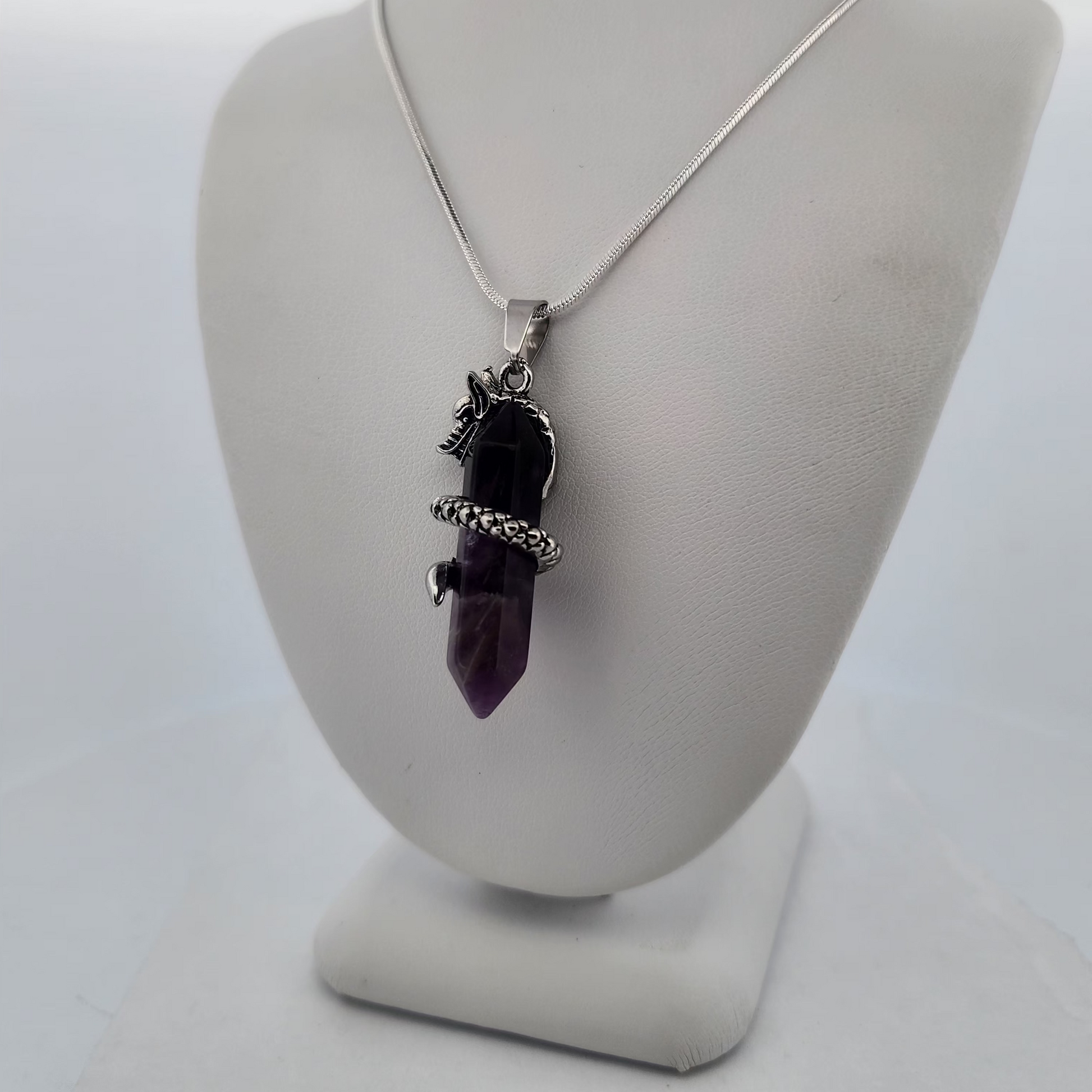 Necklace with a purple crystal pendant on a gray bust