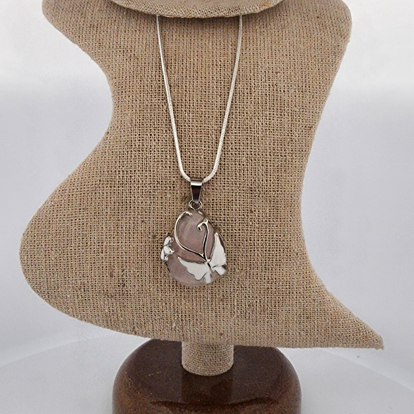 Necklace with a silver pendant on a mannequin bust against a white background