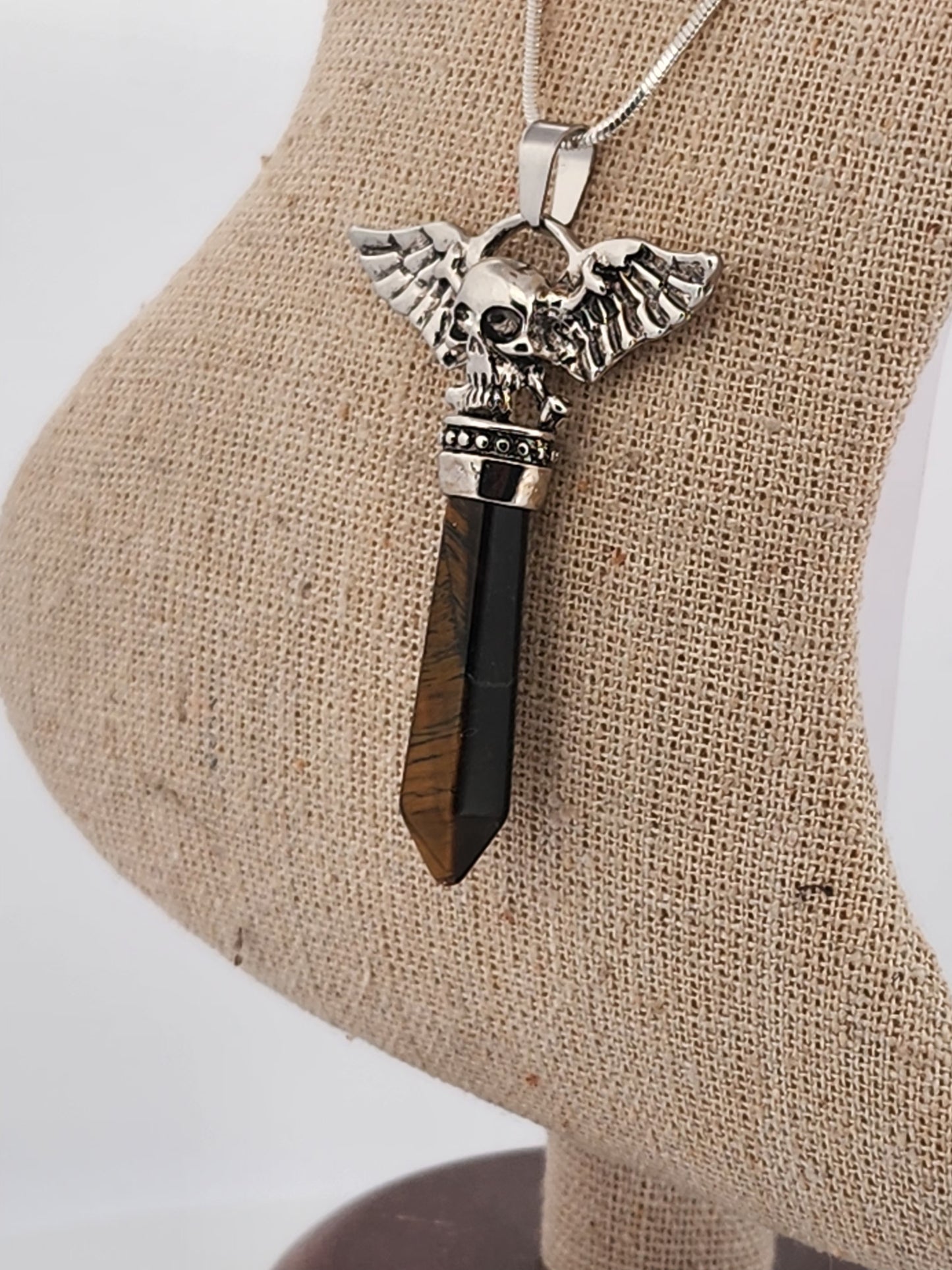 Silver pendant with black stone on a beige stand