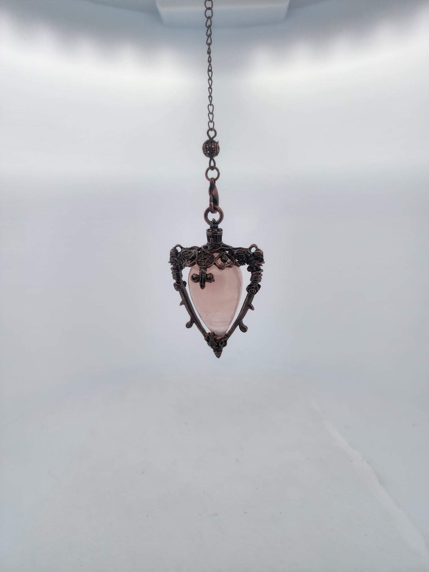 Pink stone pendant on a chain against a white background