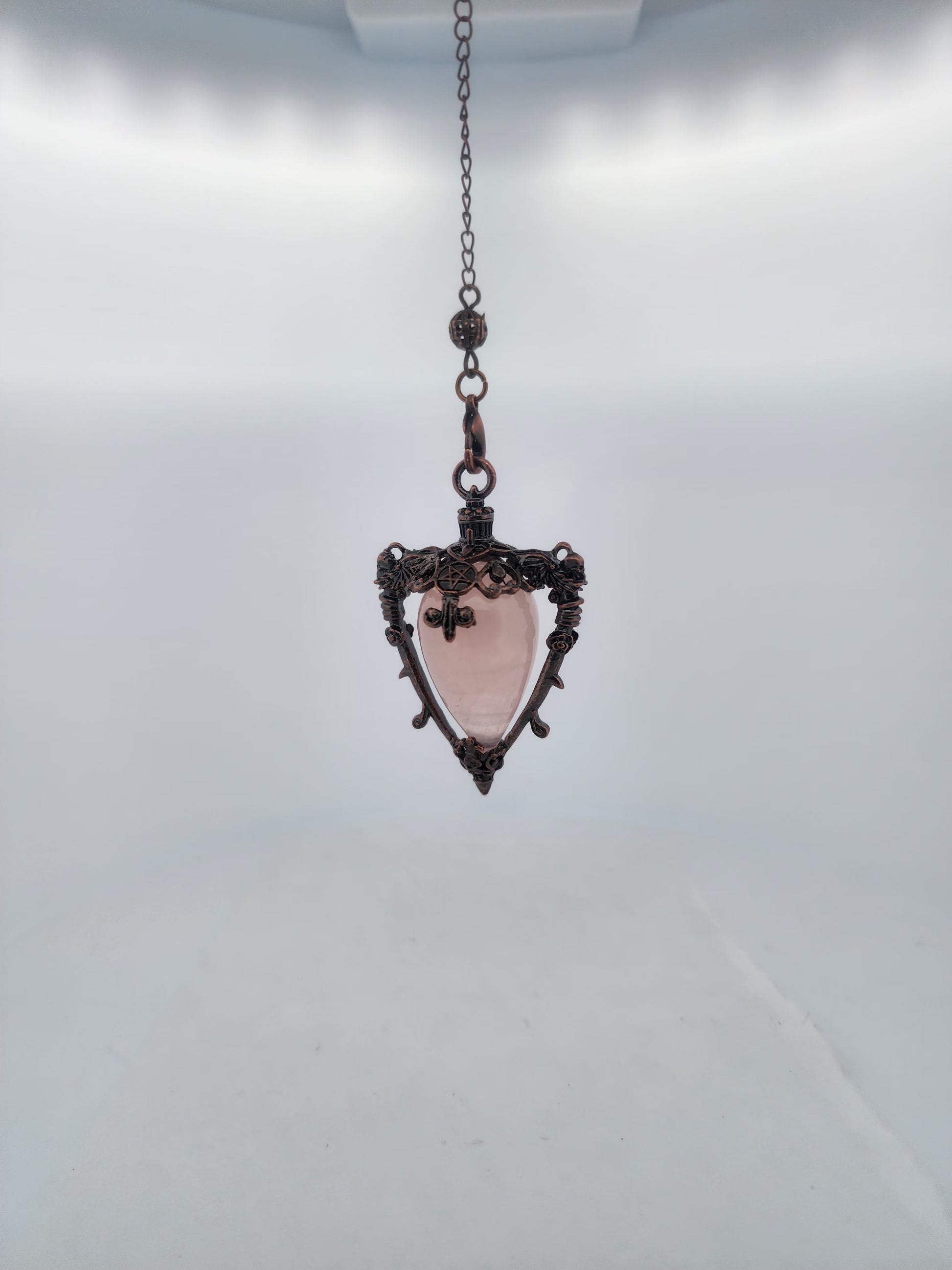 Pink stone pendant on a chain against a white background