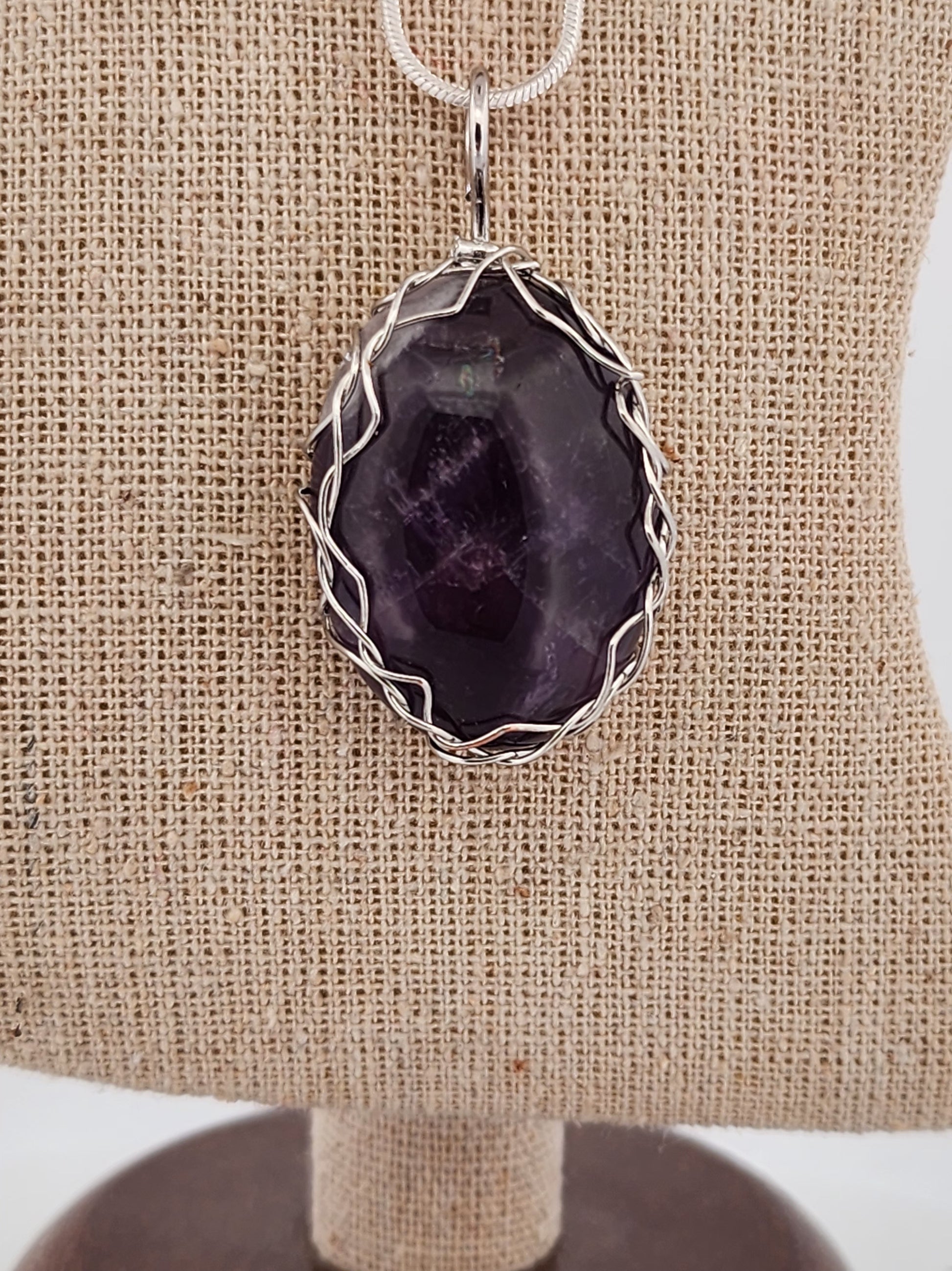 Amethyst pendant necklace on a beige fabric background