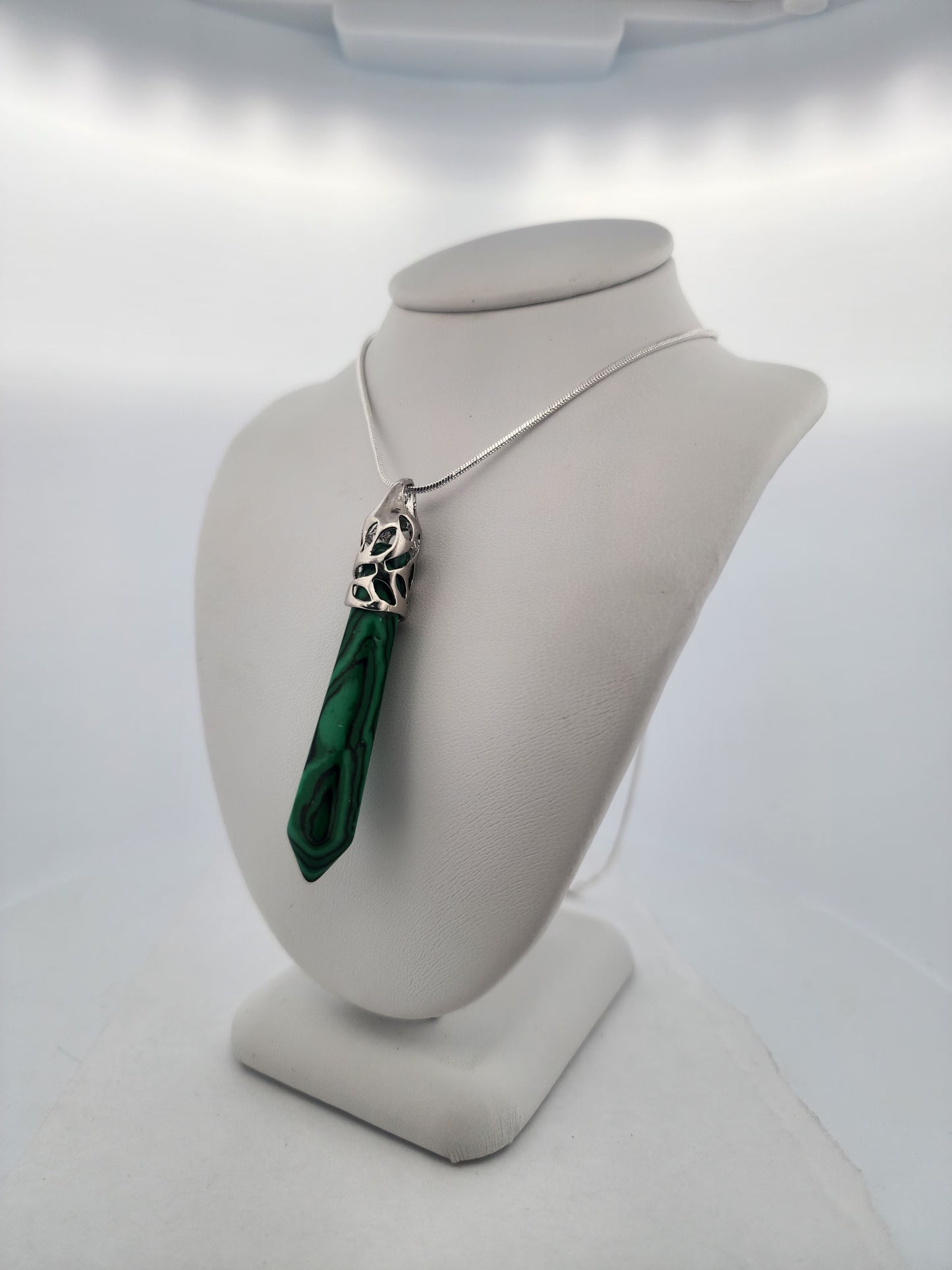 Green pendant necklace on a mannequin bust against a white background