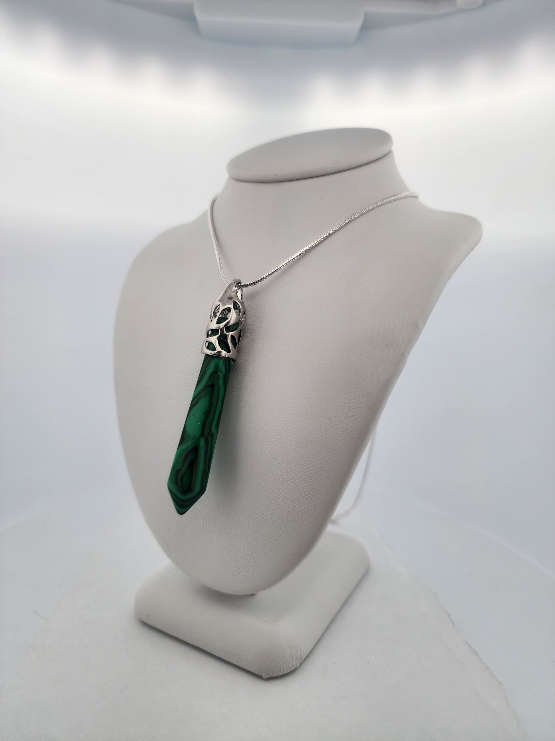 Green pendant necklace on a mannequin bust against a white background
