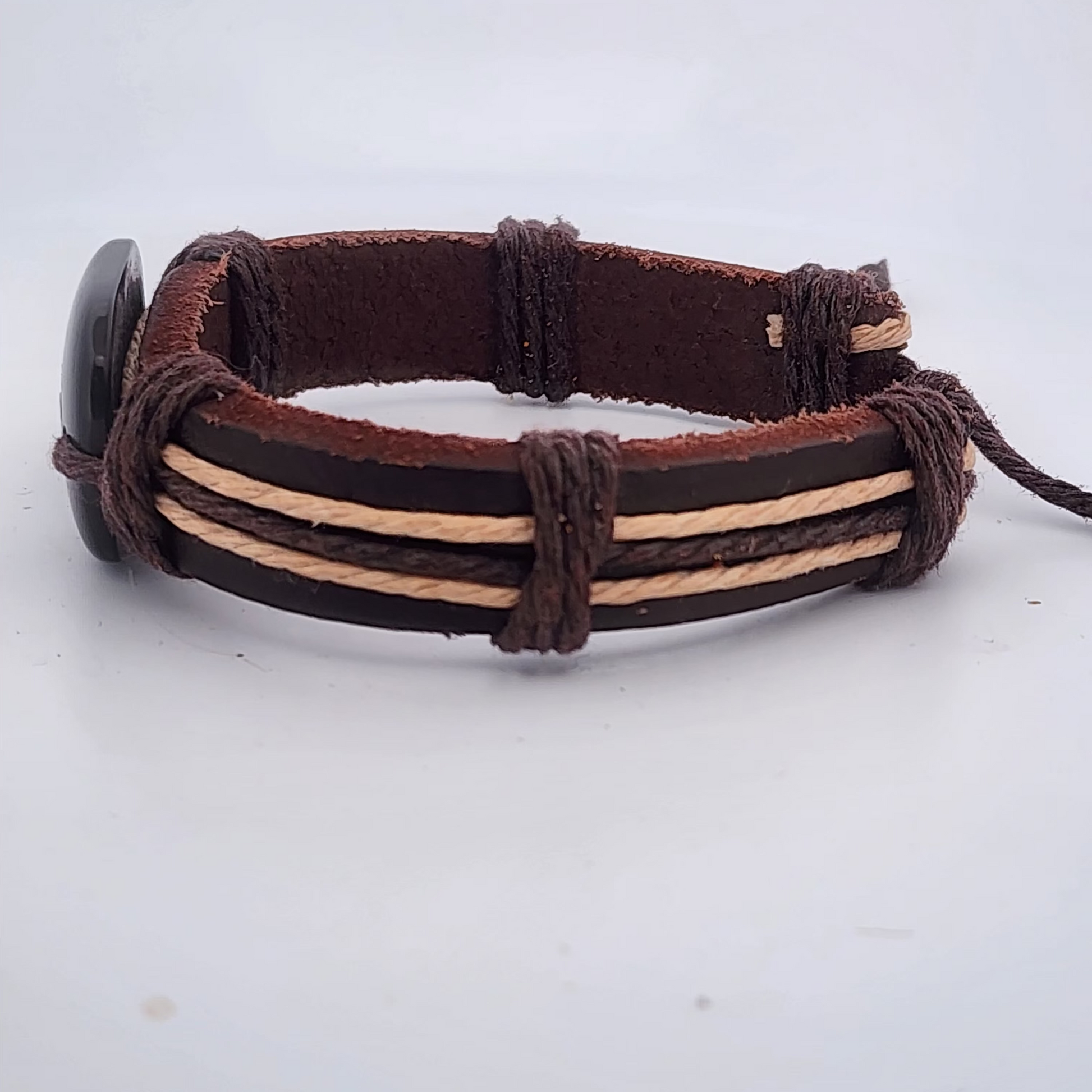 Brown leather bracelet with braided design on a light gray background