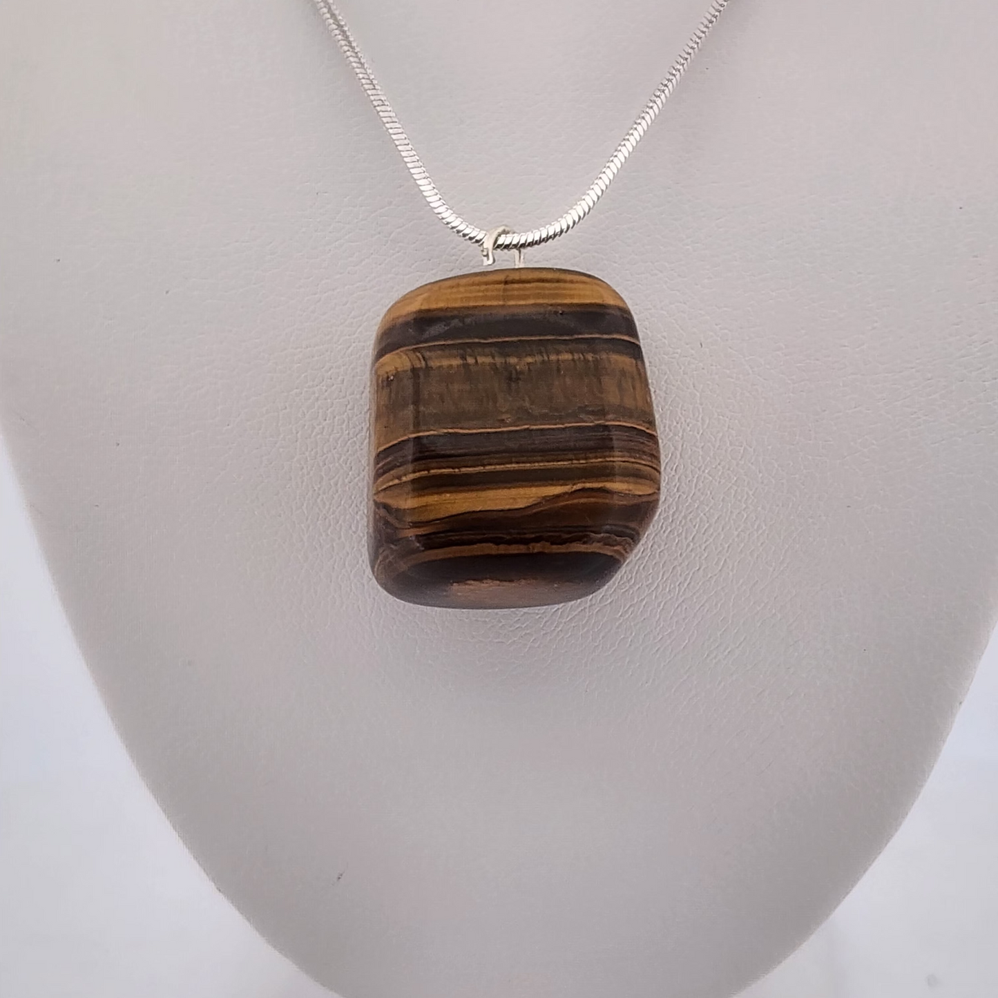 Tiger's eye pendant on a silver chain against a white background