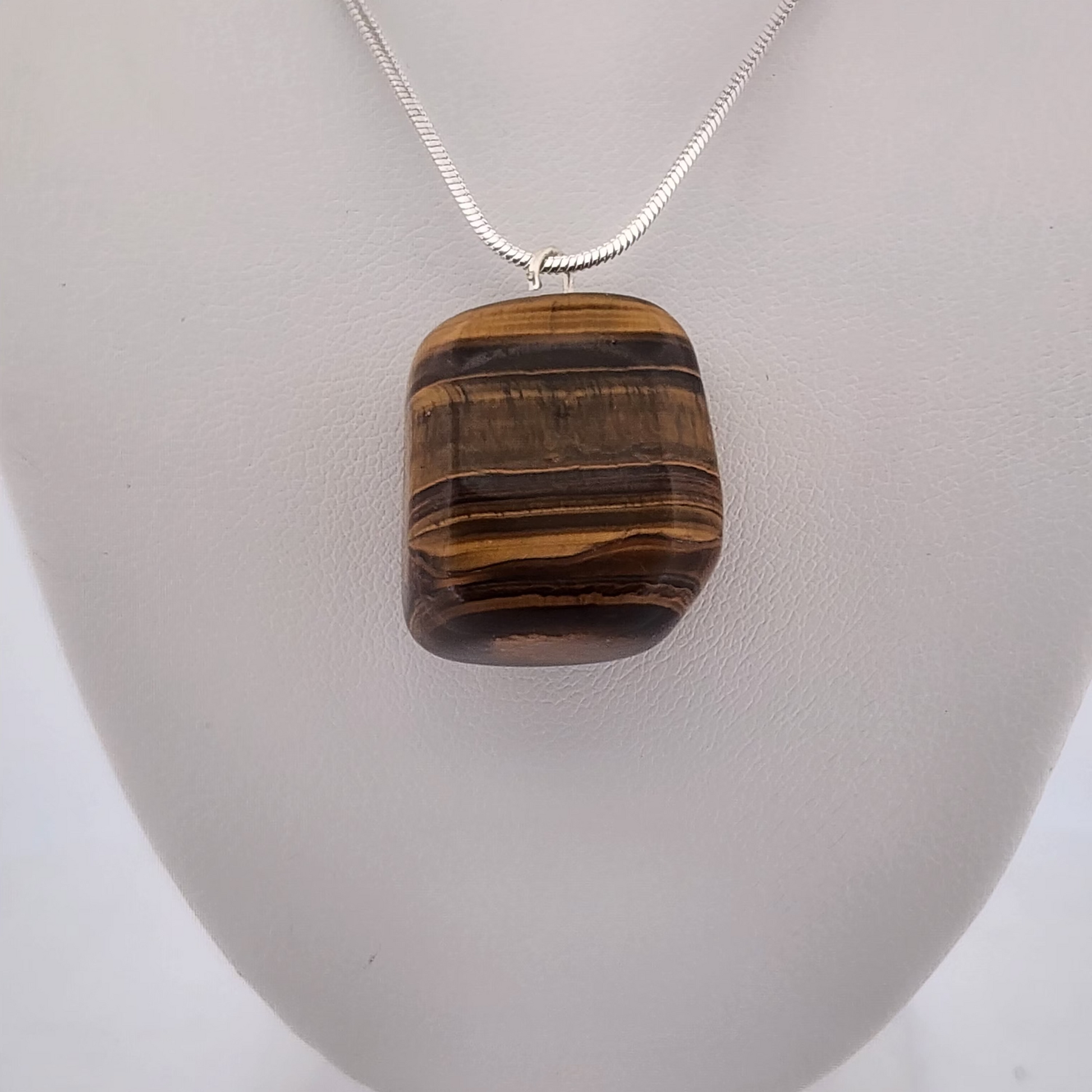 Tiger's eye pendant on a silver chain against a white background
