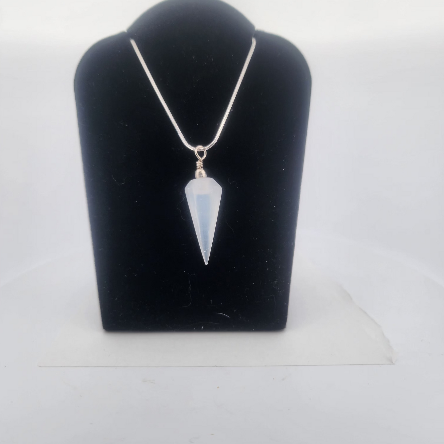 Necklace with a pendant on a black velvet stand against a white background