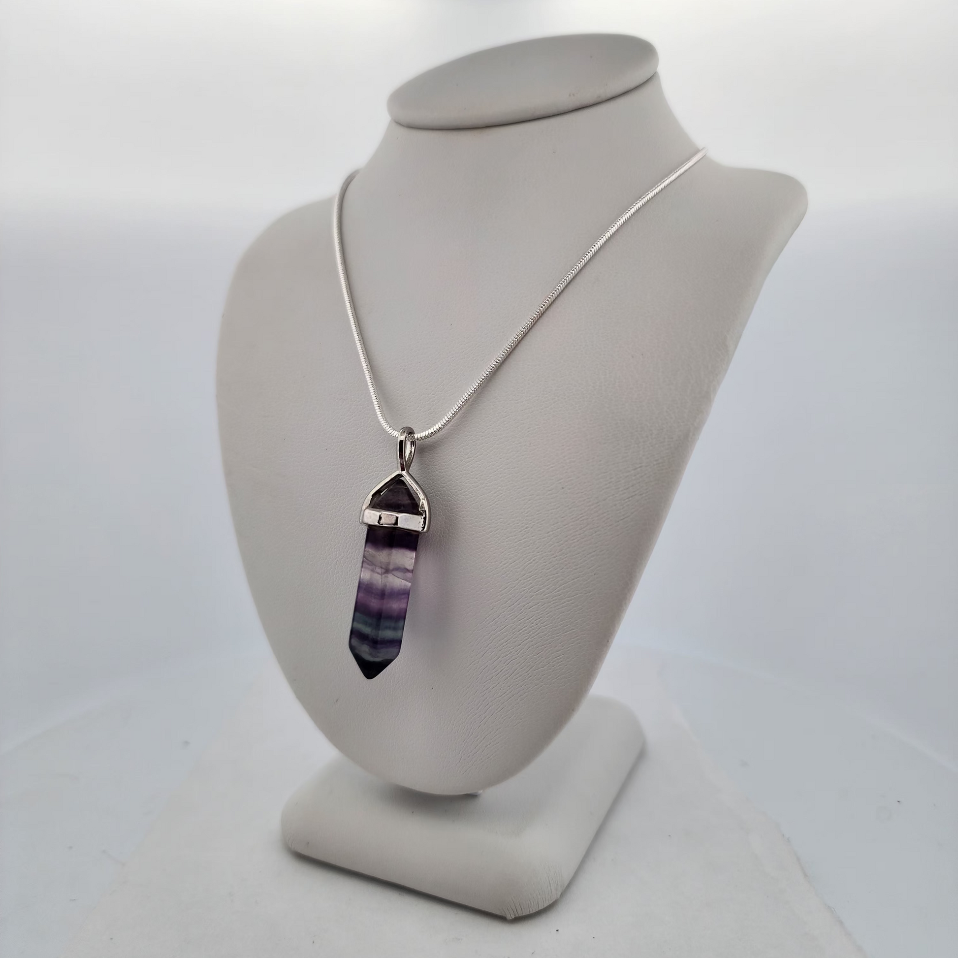 Necklace with a purple crystal pendant on a white mannequin bust.