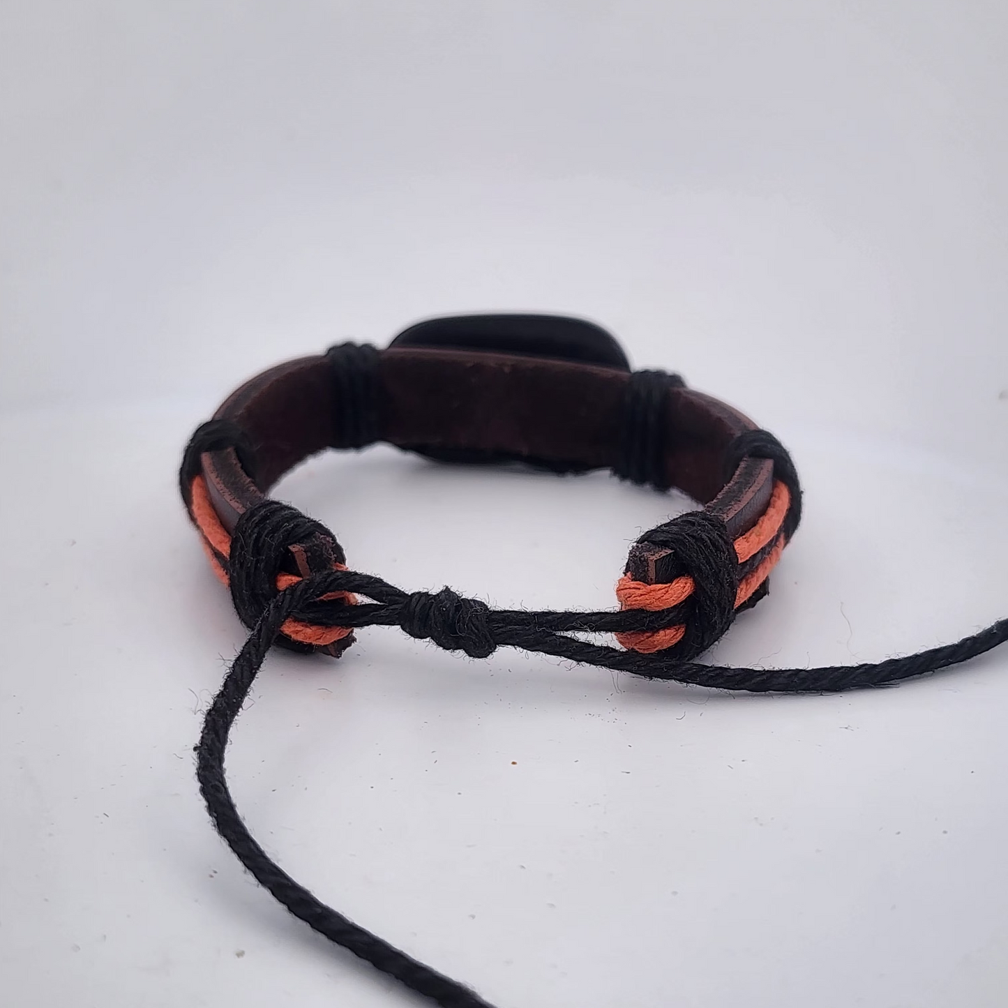 Bracelet with black and orange cord on a white background