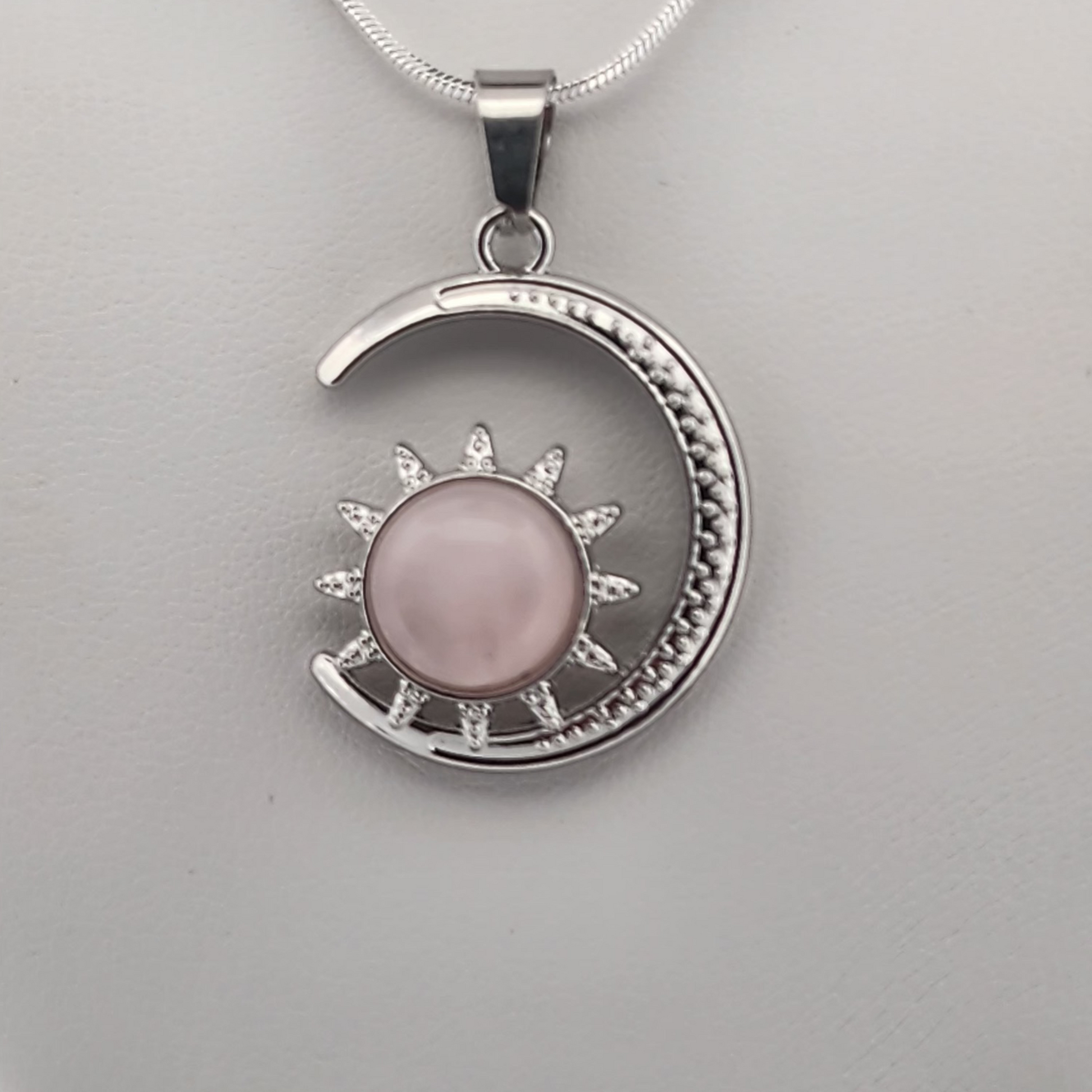 Silver pendant with pink stone on a gray background