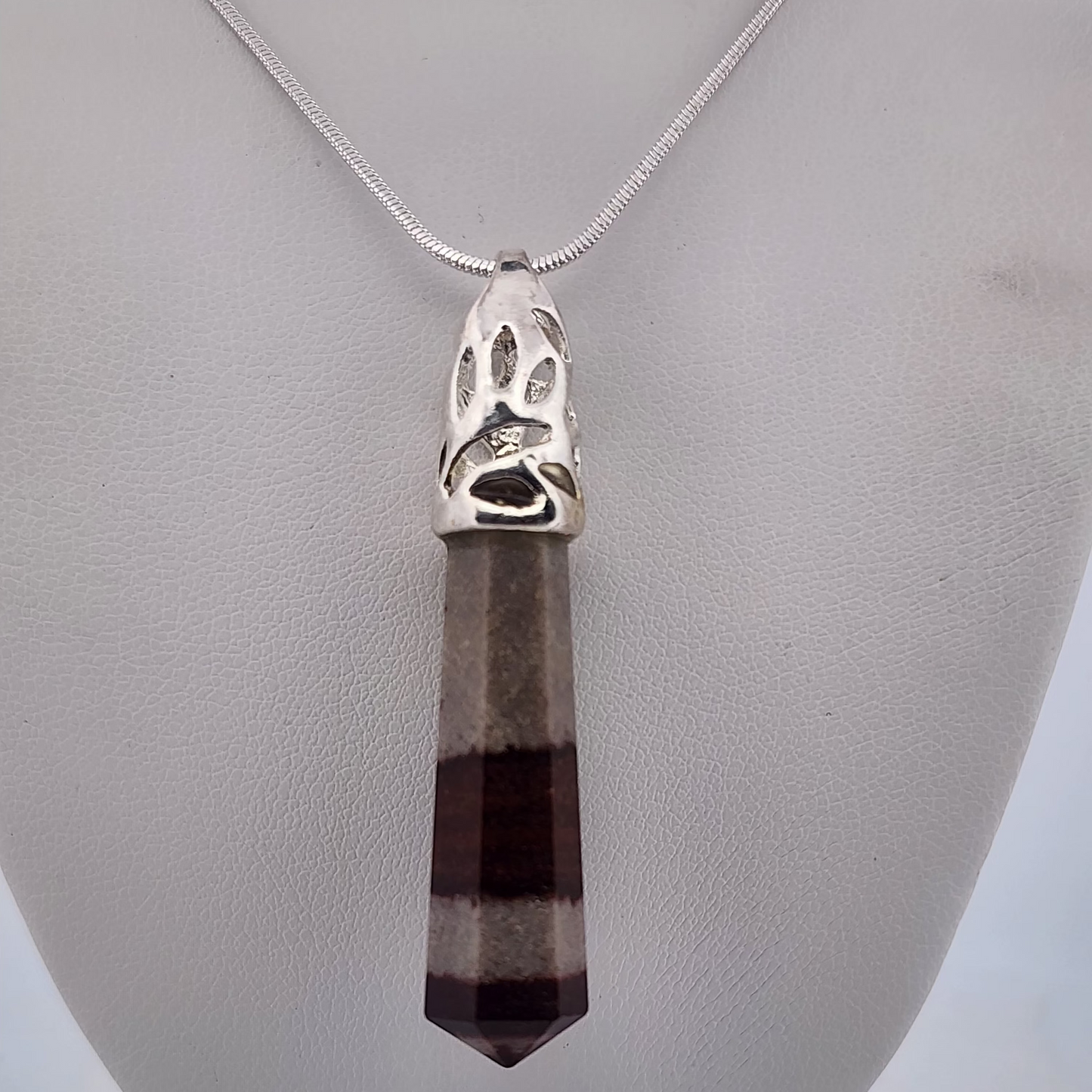 Necklace with a pendant featuring a paw print design on a gray stand.