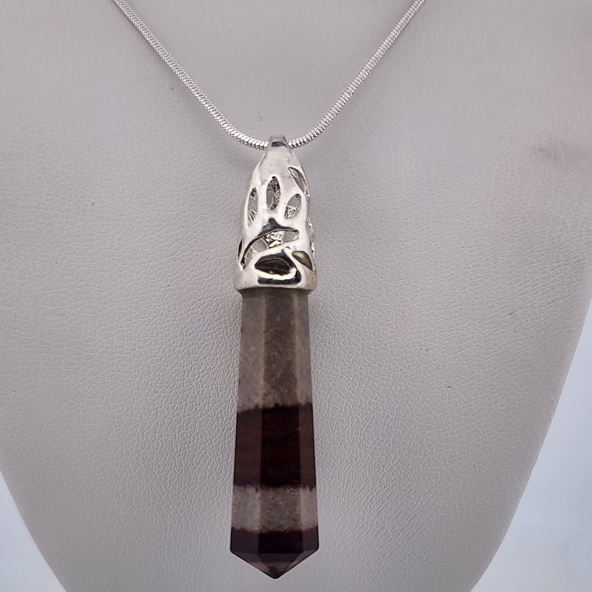 Necklace with a pendant featuring a paw print design on a gray stand.