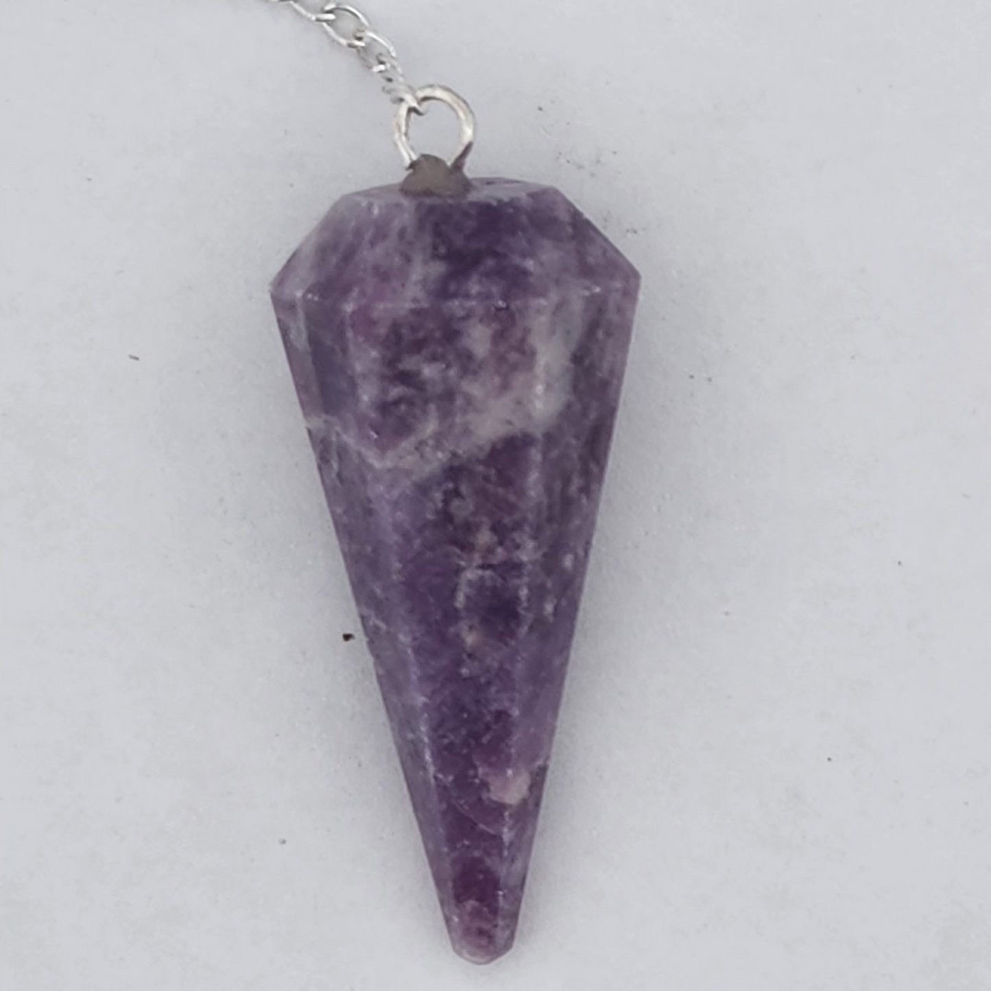 Amethyst pendulum on a silver chain against a white background