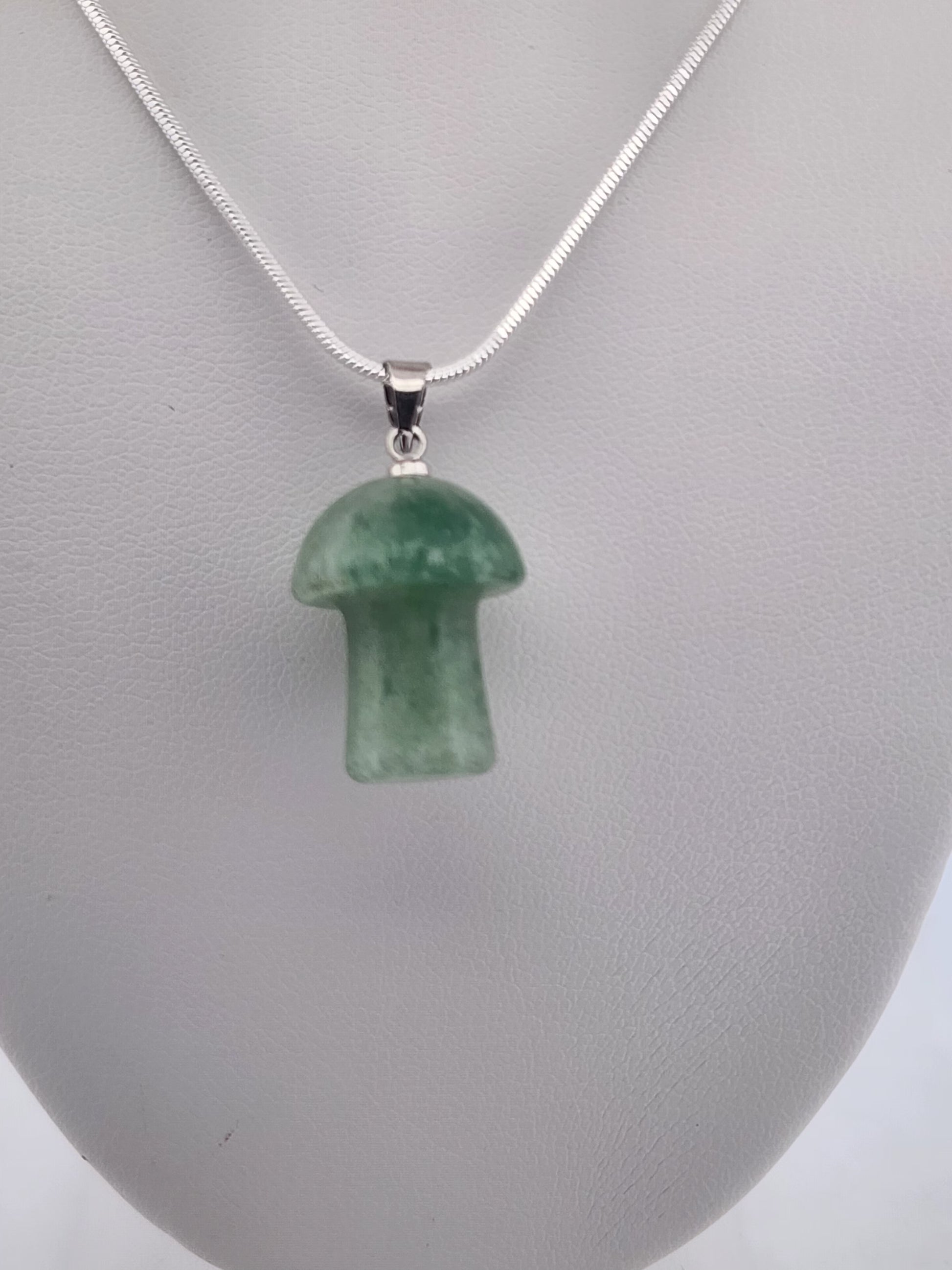 Green mushroom-shaped pendant on a silver chain against a gray background