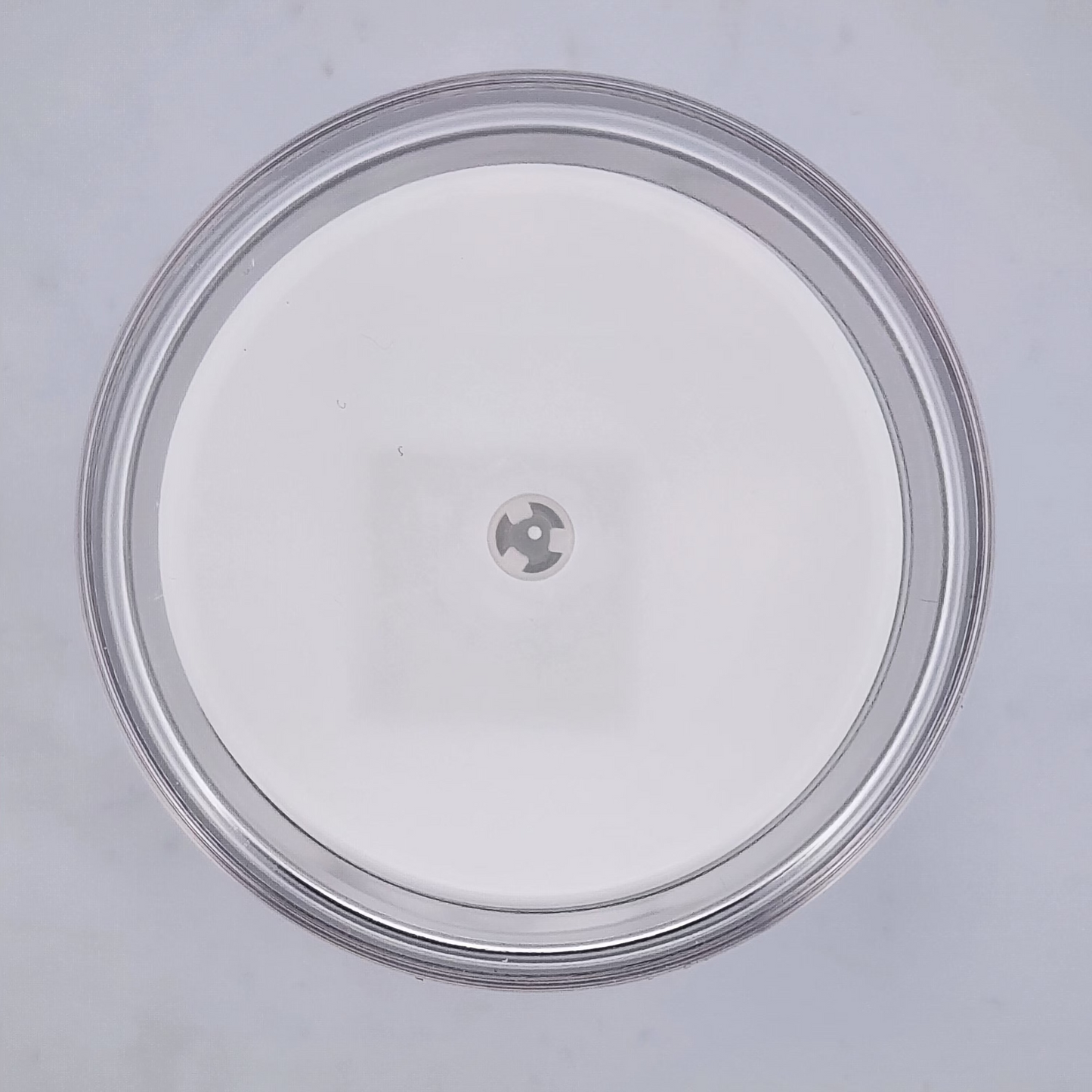 Clear plastic lid with a central hole on a gray background