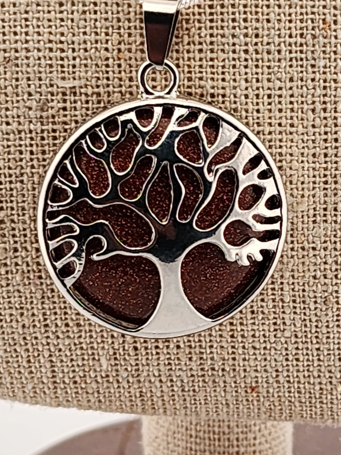 Tree of life pendant on a beige fabric background