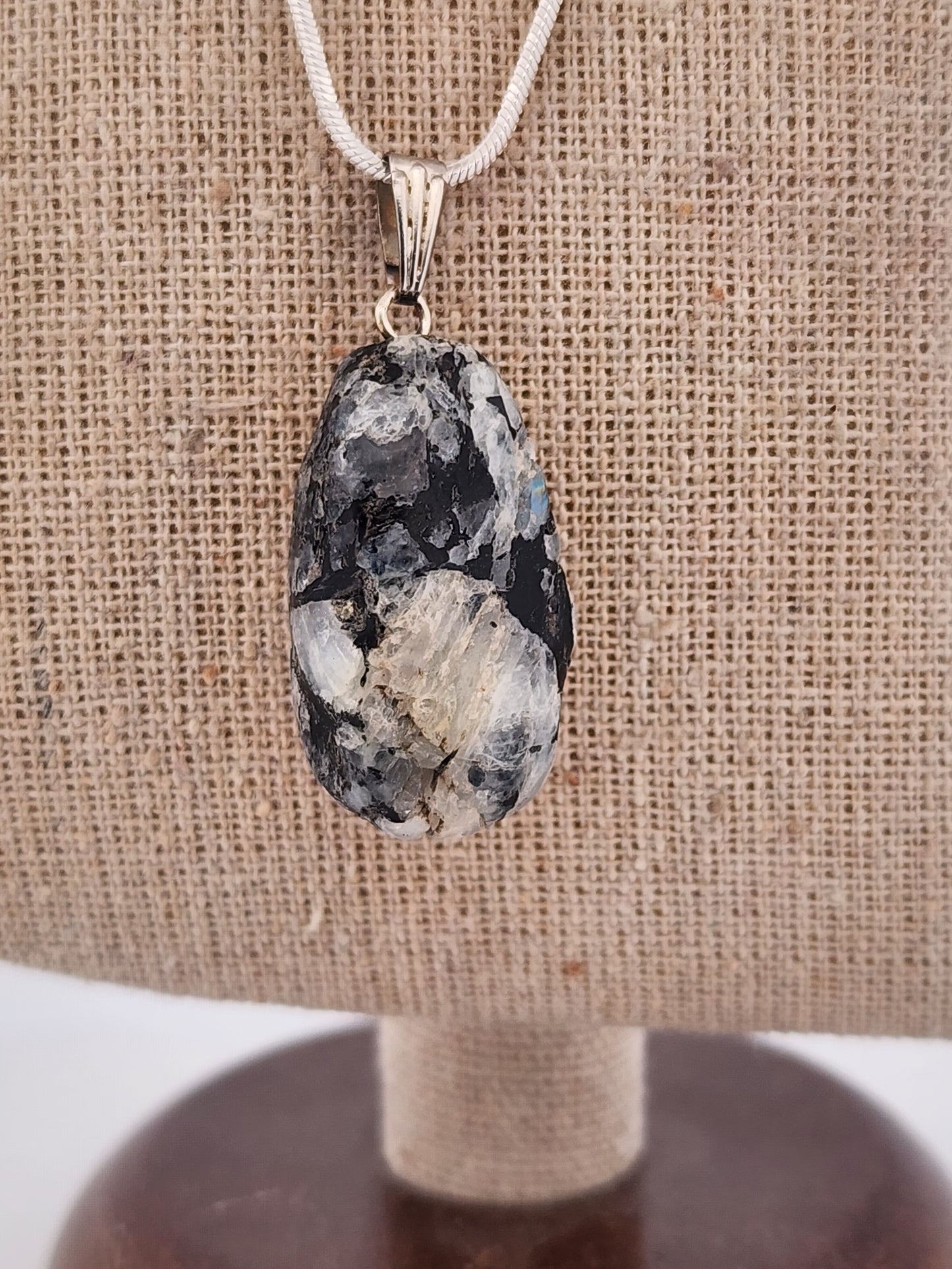 Necklace with a large, textured pendant on a burlap surface