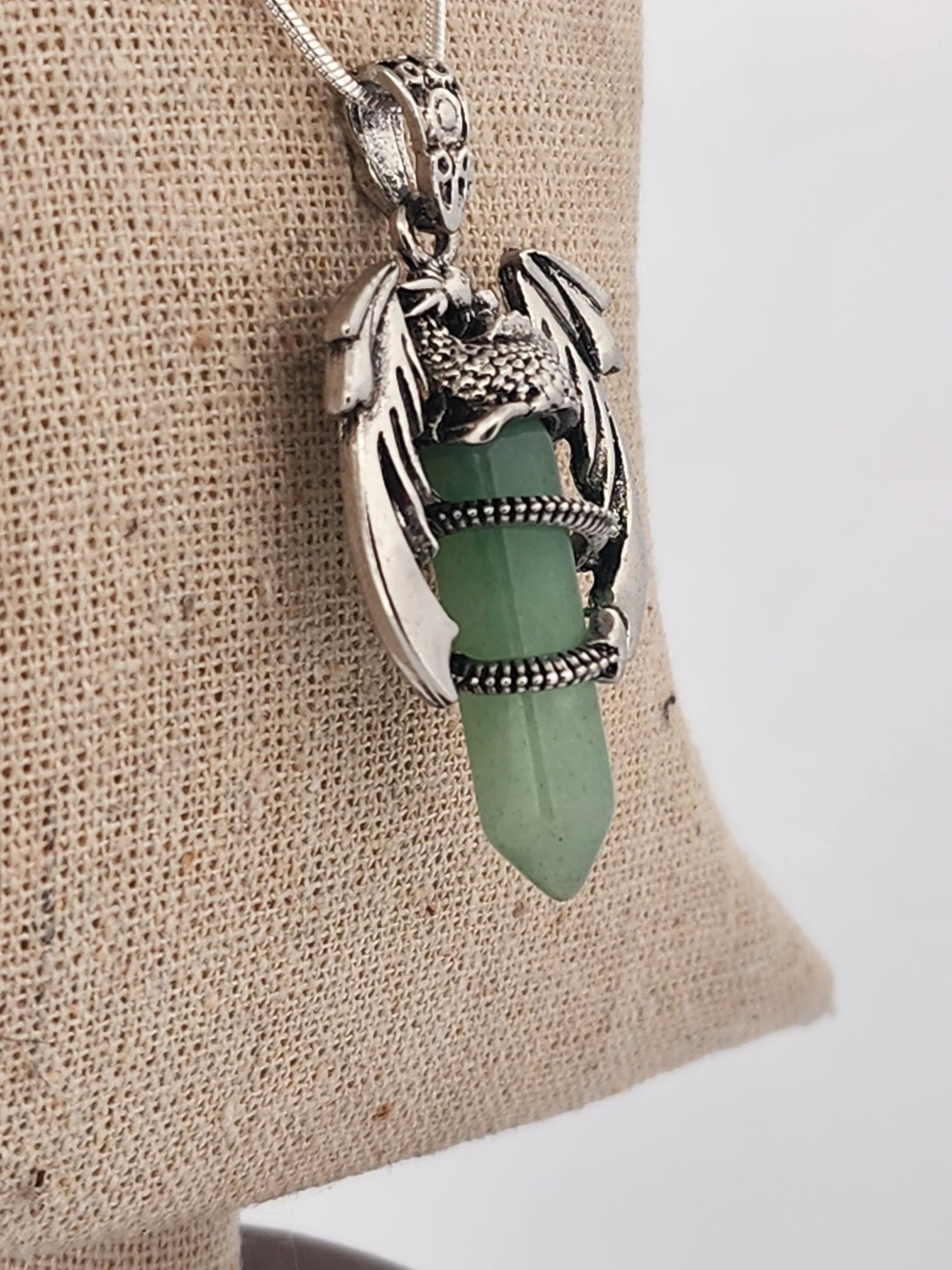 Green crystal pendant with silver holder on beige fabric