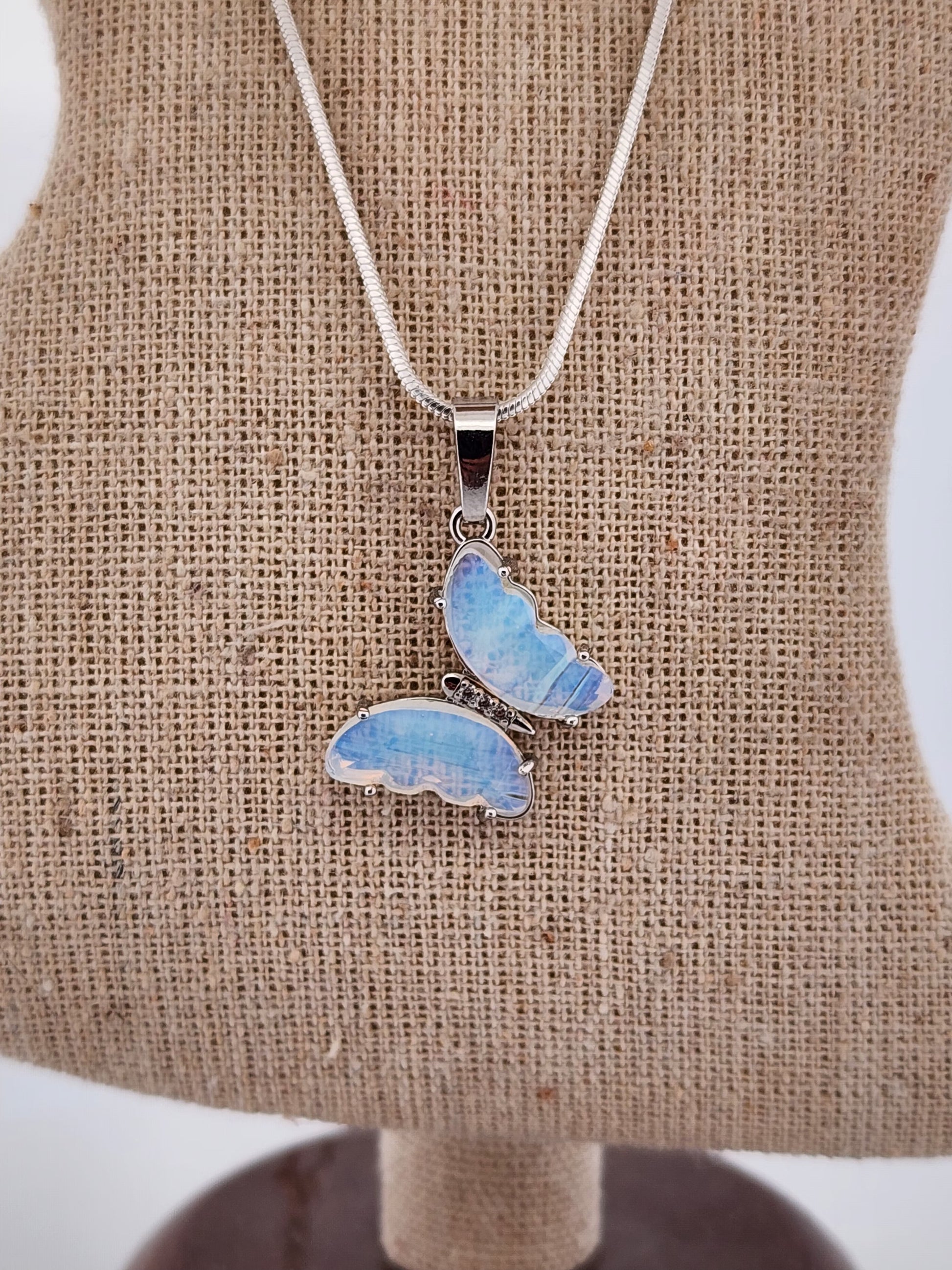 Butterfly-shaped pendant on a chain displayed on a mannequin bust.