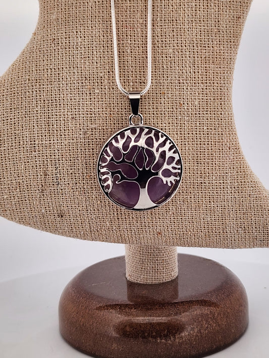 Necklace with a purple and white tree-of-life pendant on a brown jewelry stand.