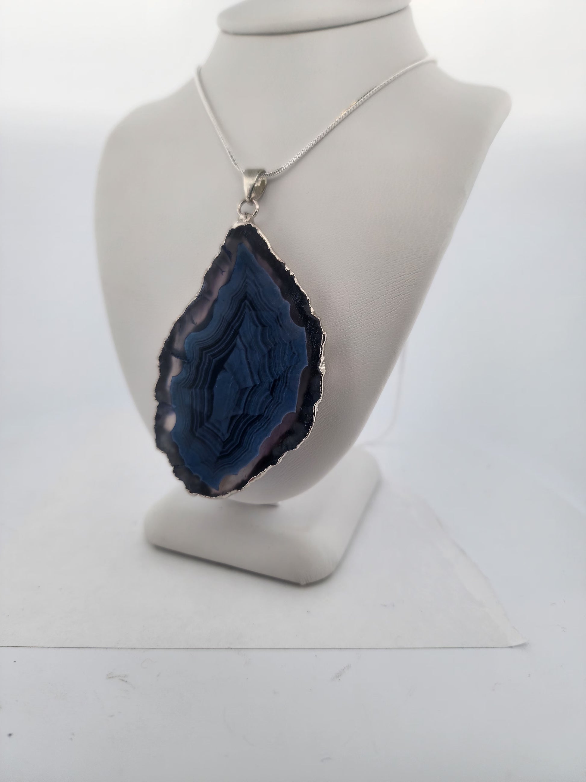 Blue agate pendant on a mannequin bust against a white background