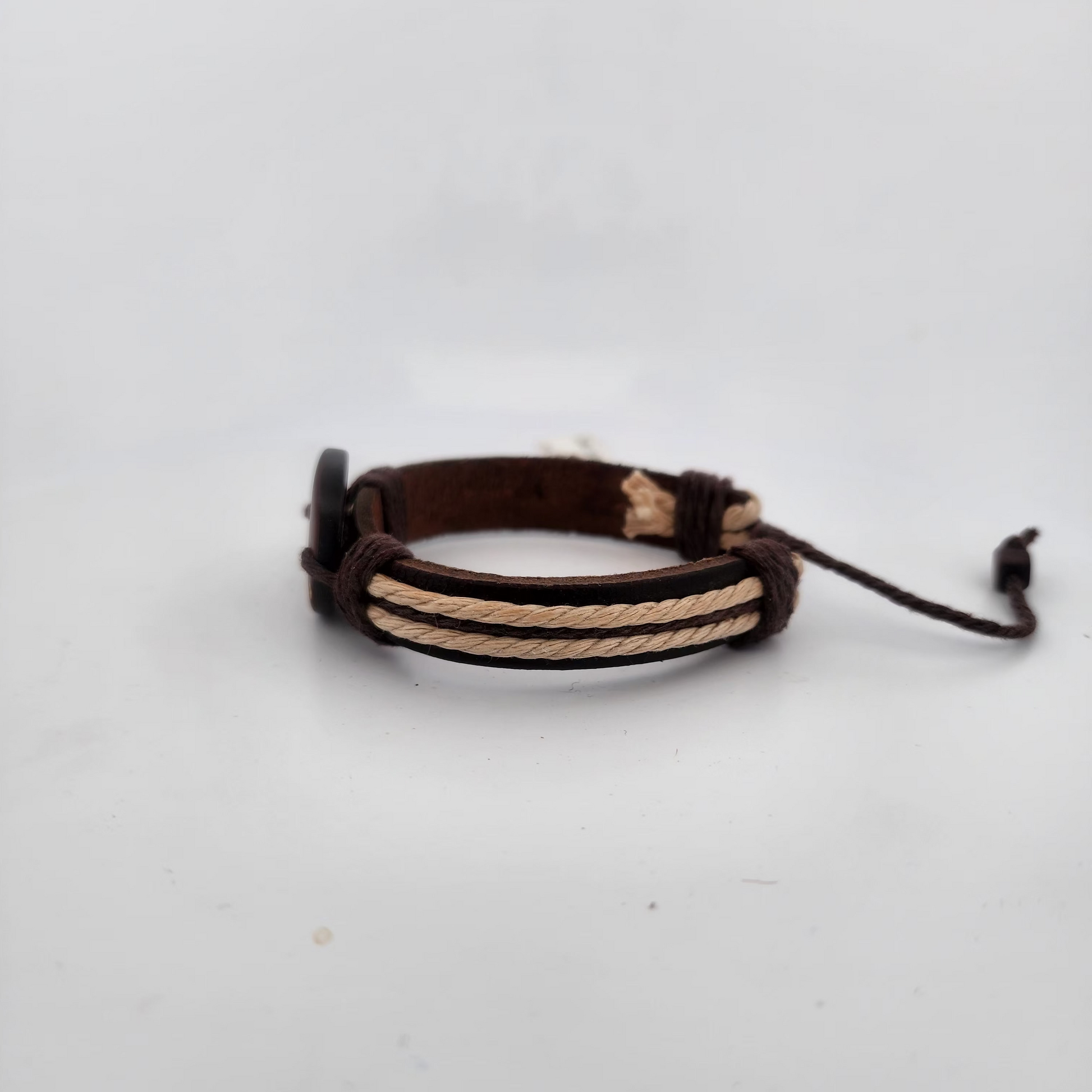 Brown leather bracelet with beige cord on a white background