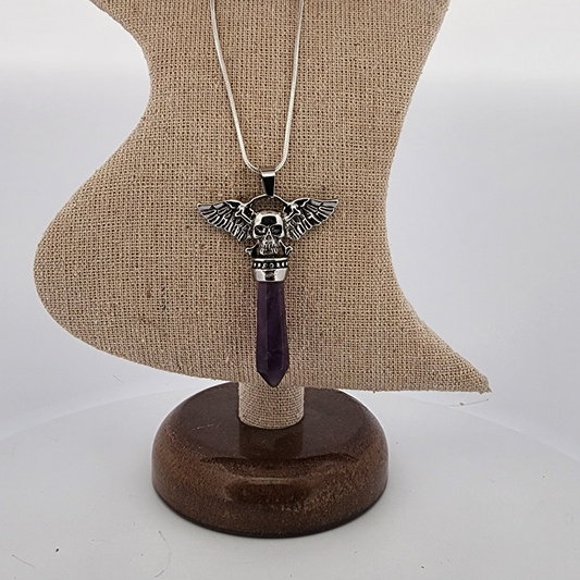 Necklace with a skull and wings pendant on a wooden stand against a white background