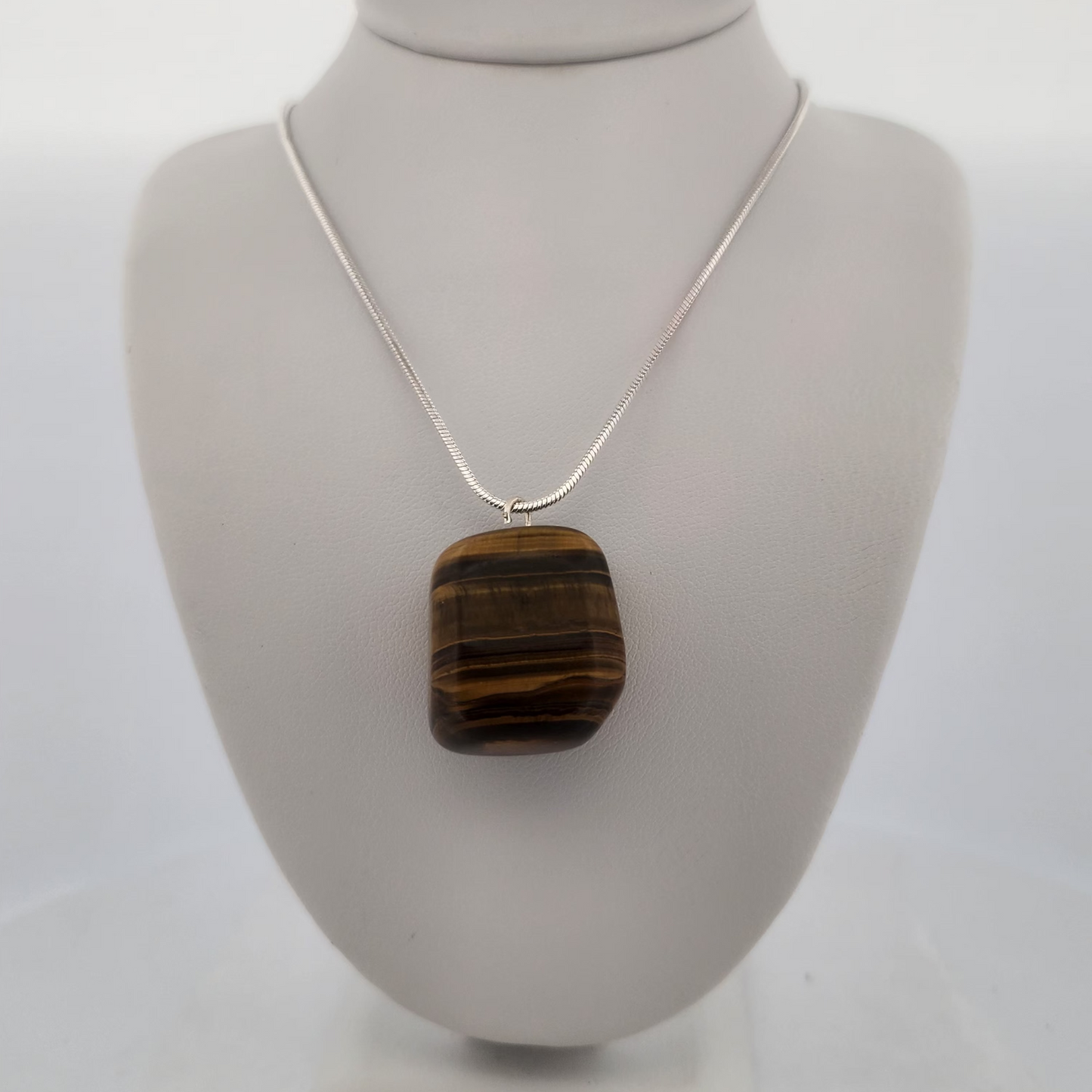 Necklace with a square brown pendant on a white mannequin bust.