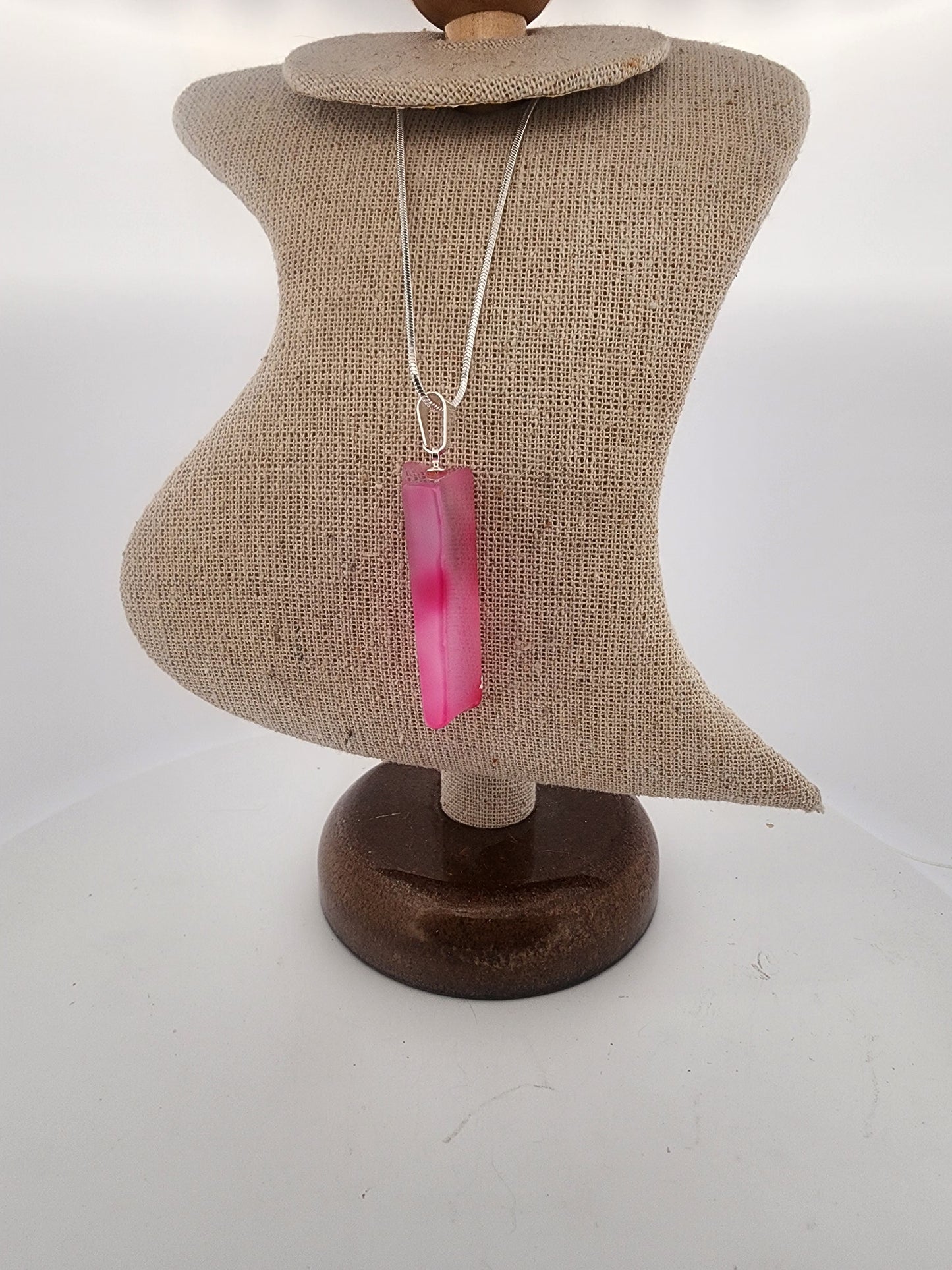 Necklace with a pink pendant on a mannequin bust against a white background