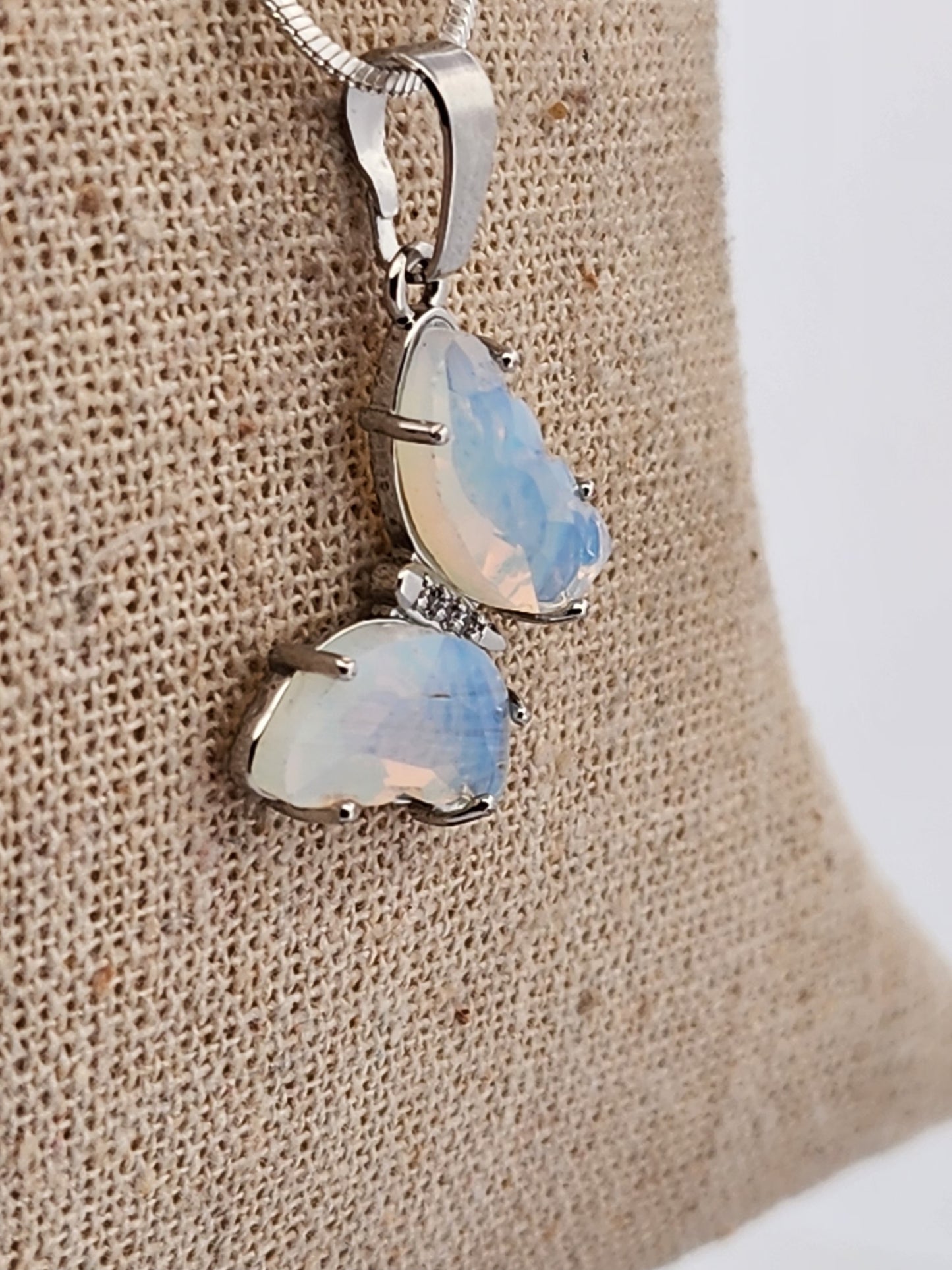 Opal pendant necklace on a textured beige surface