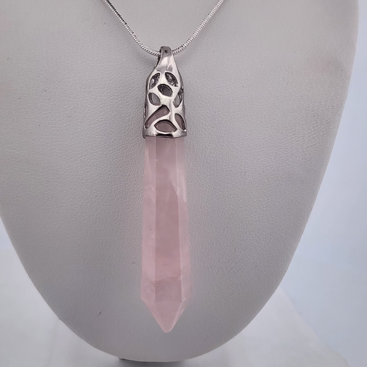Necklace with a pink crystal pendant on a mannequin bust.