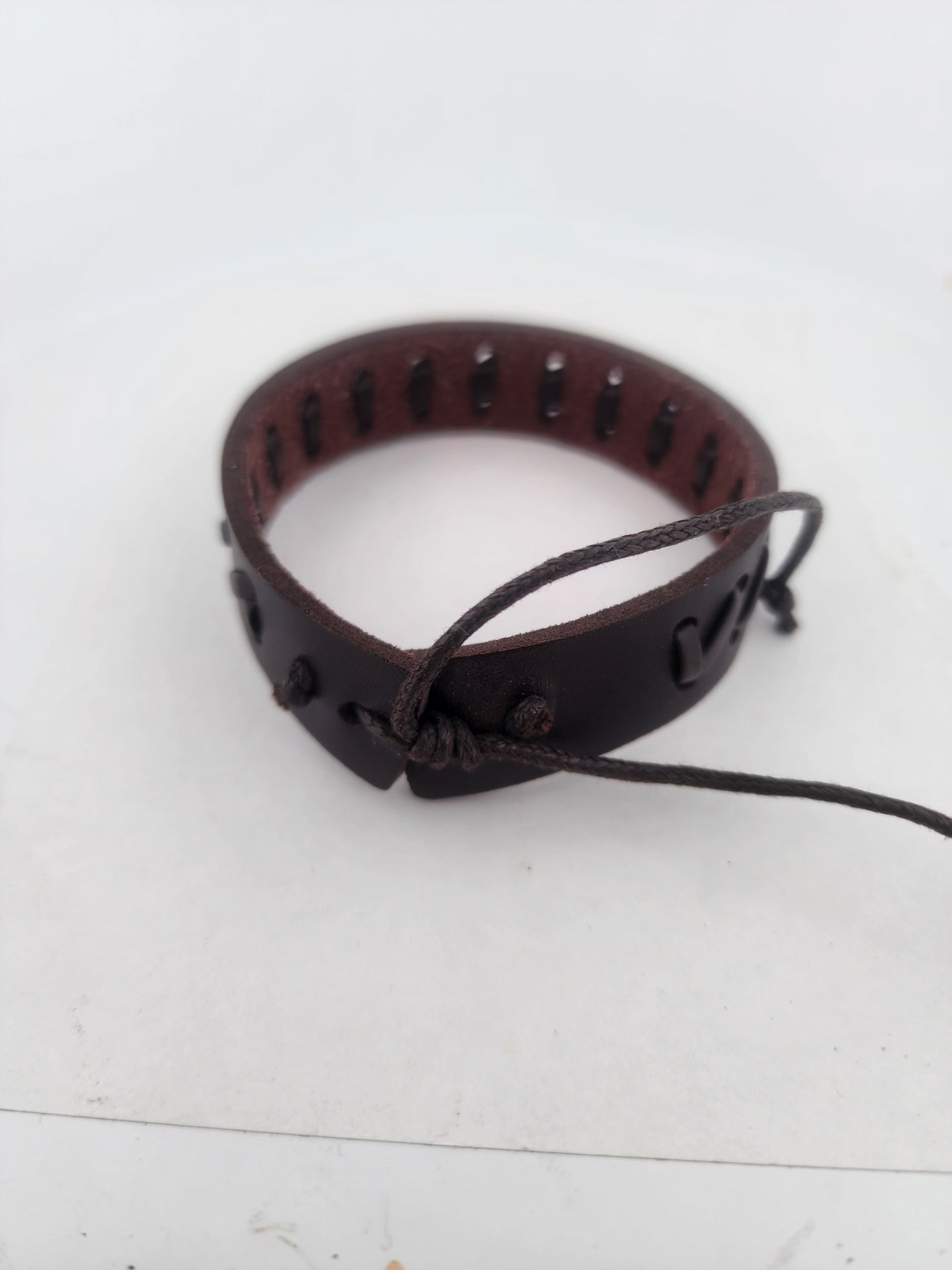 Brown leather bracelet with cut-out design on a white background