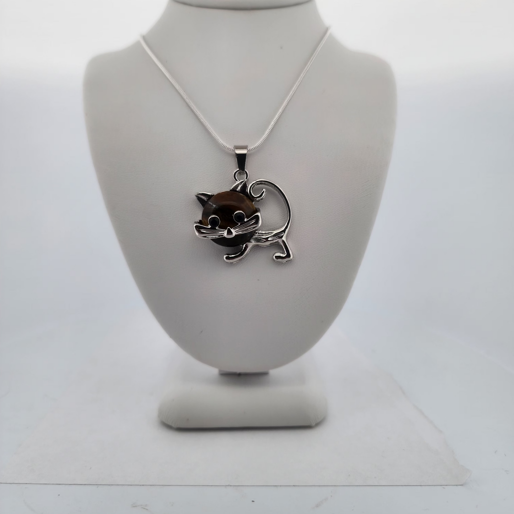 Silver necklace with a cat pendant on a white stand against a white background