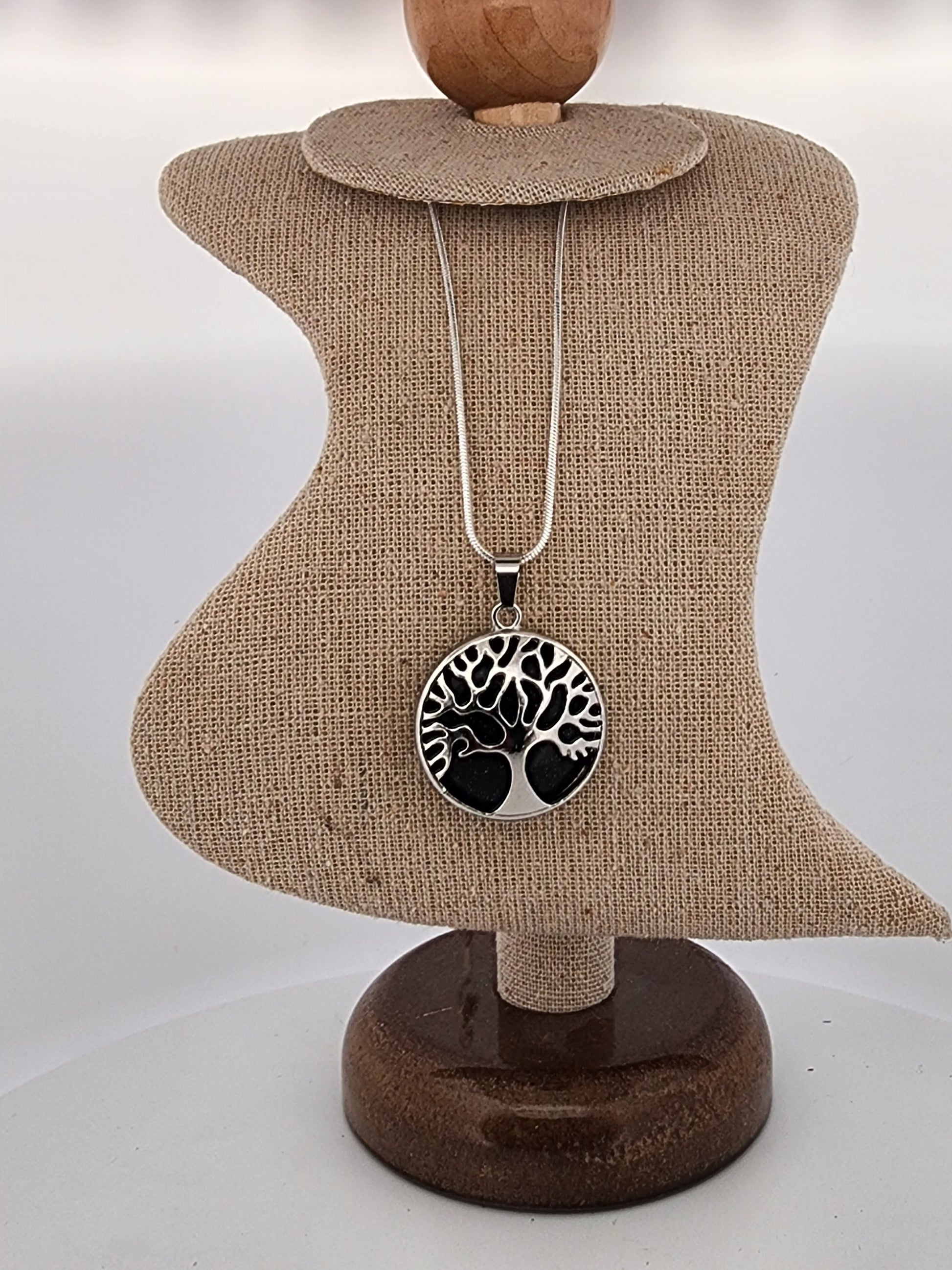 Necklace with a tree of life pendant on a mannequin bust.