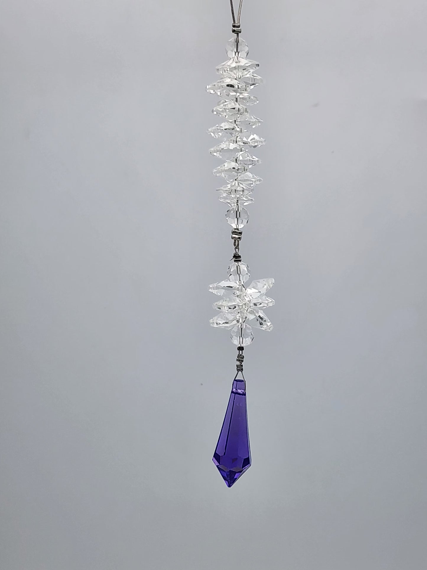 Crystal pendant with a purple teardrop on a gray background