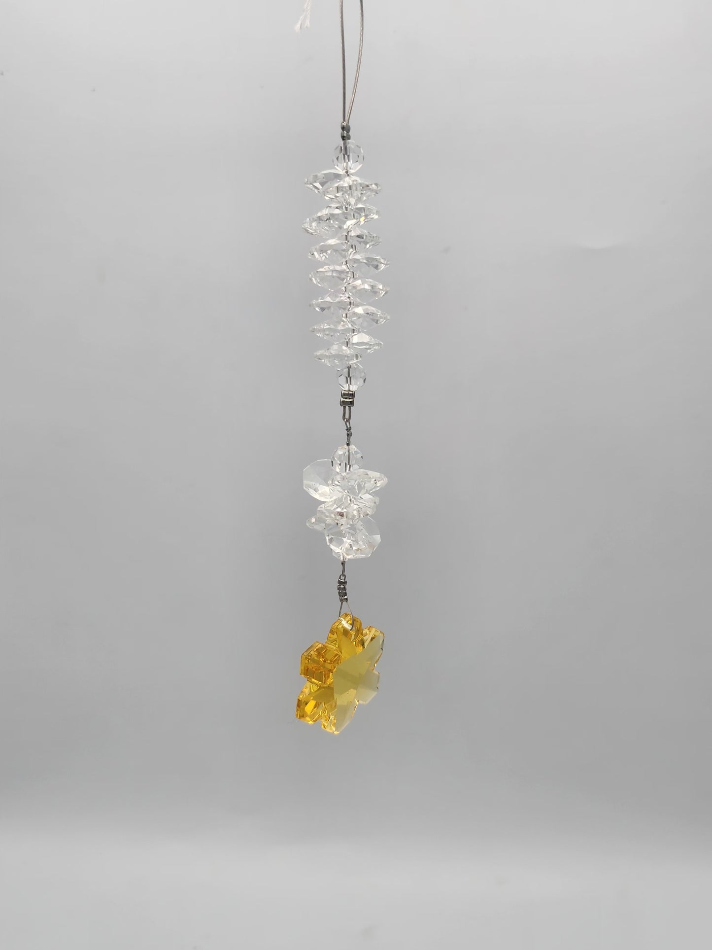 Crystal hanging ornament with a yellow crystal on a gray background