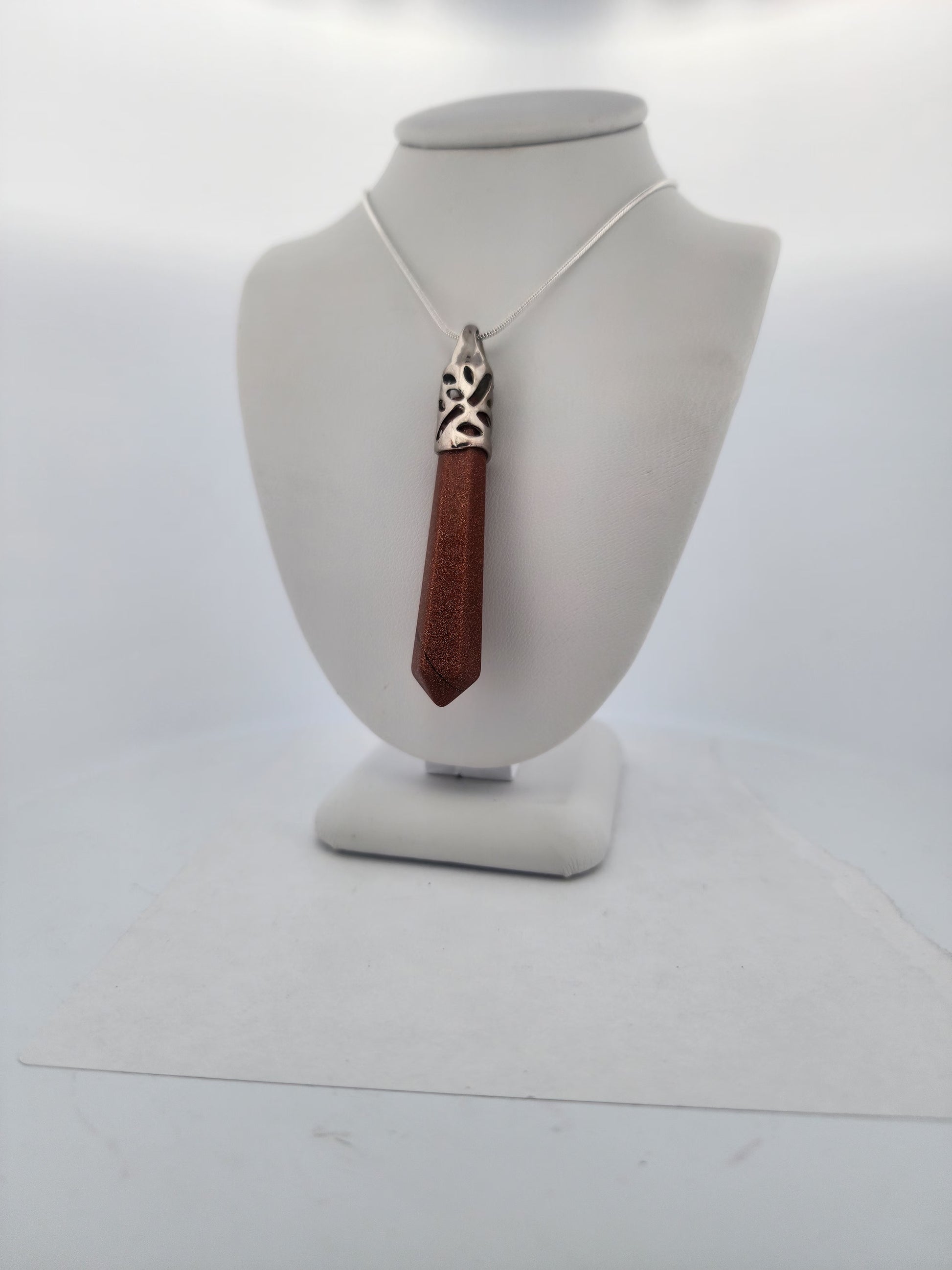 Necklace with a red pendant on a white mannequin bust against a white background