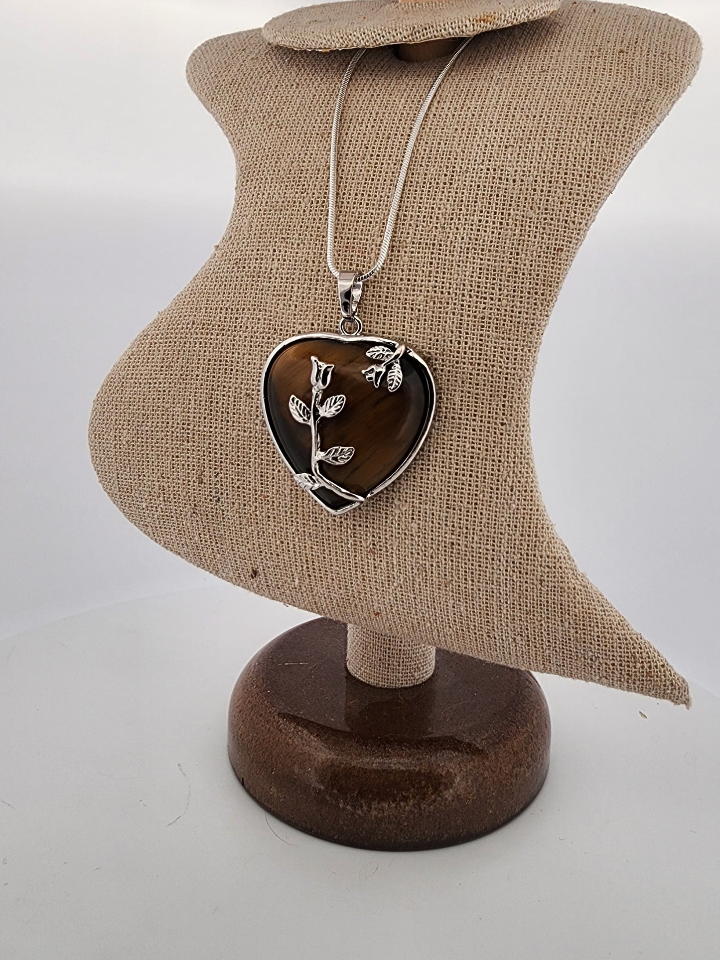 Heart-shaped pendant with floral design on a brown bust