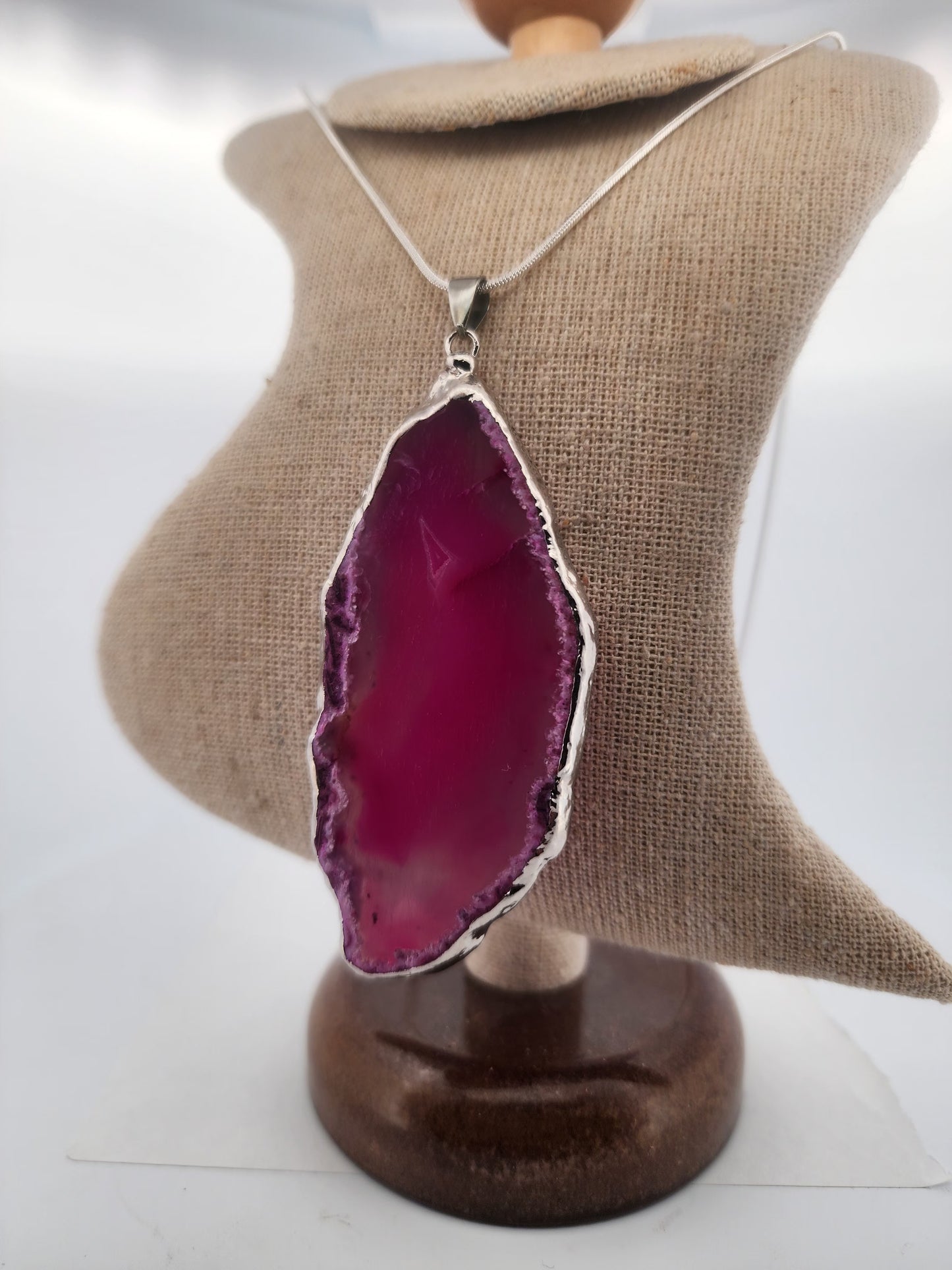 Necklace with a pink agate pendant on a mannequin bust.