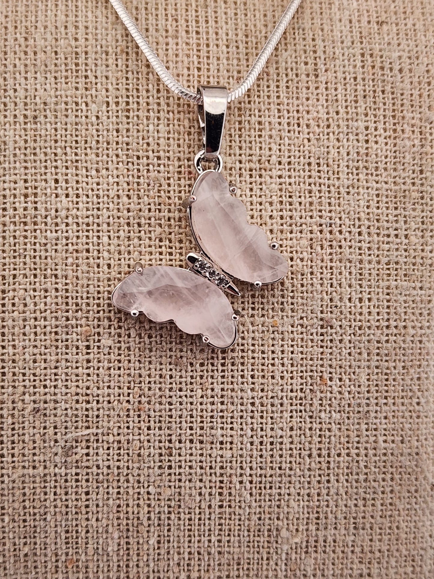 Silver necklace with two heart-shaped pendants on a textured beige background