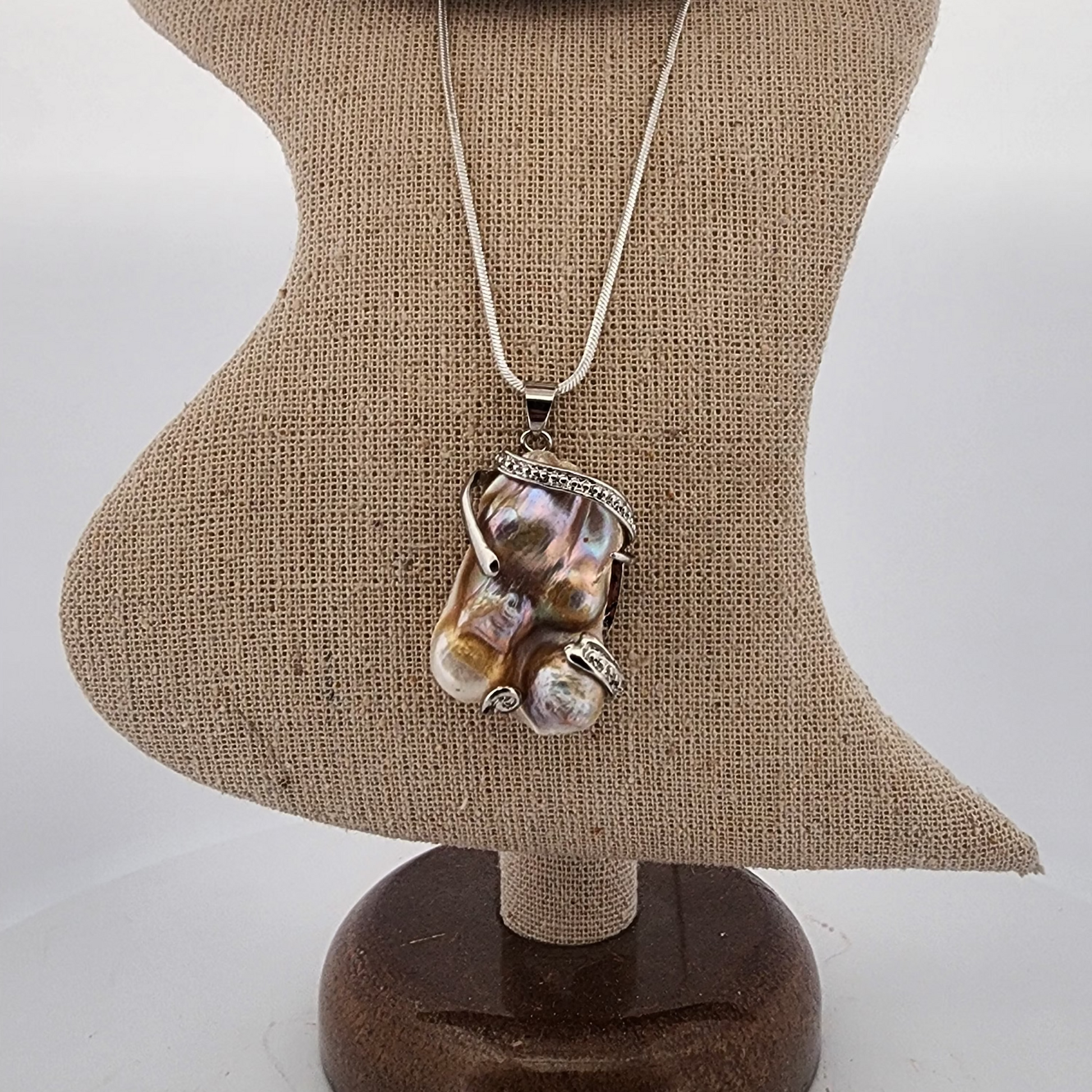 Necklace with a large, multicolored pendant on a mannequin bust.