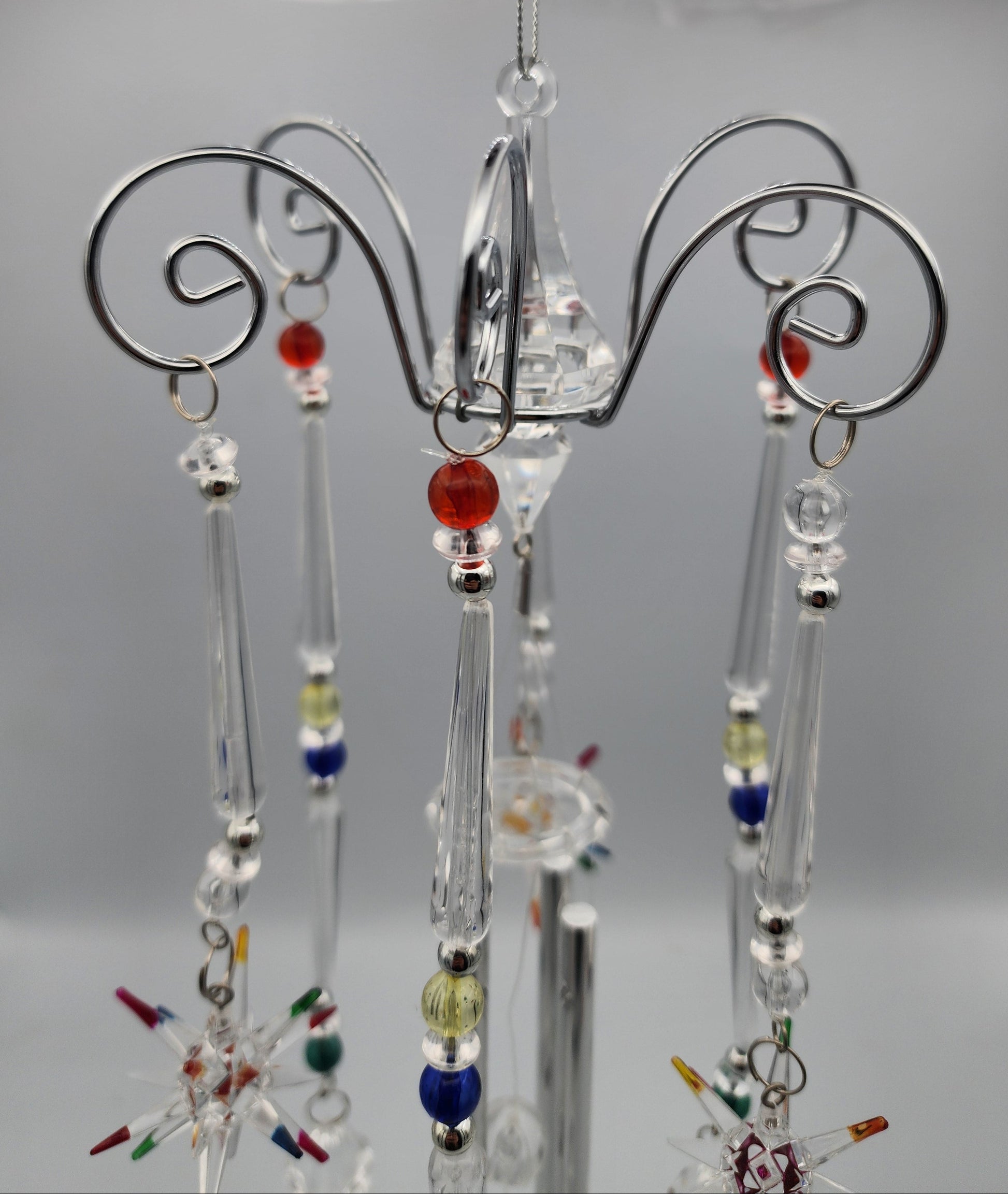 Decorative hanging mobile with colorful beads on a stand against a neutral background