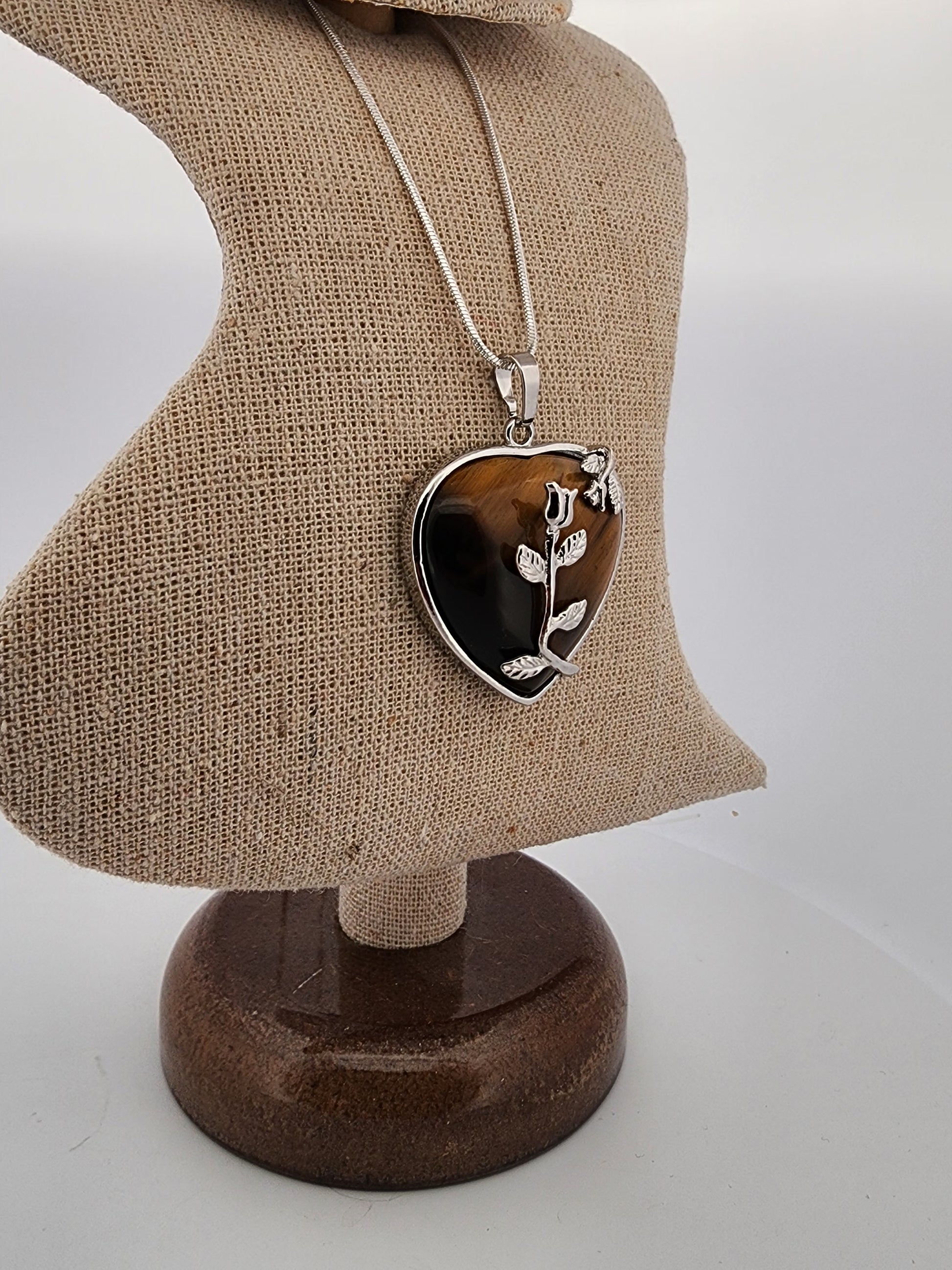 Heart-shaped pendant necklace on a mannequin bust with a plain background